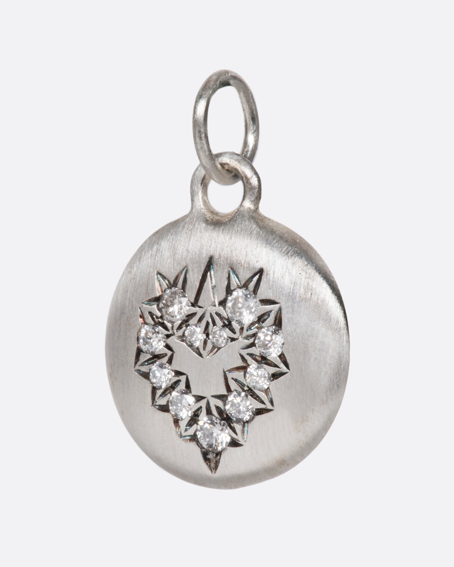 A beautiful sterling silver heart charm with striking, high quality grey diamonds surrounded by angular etching that makes them pop