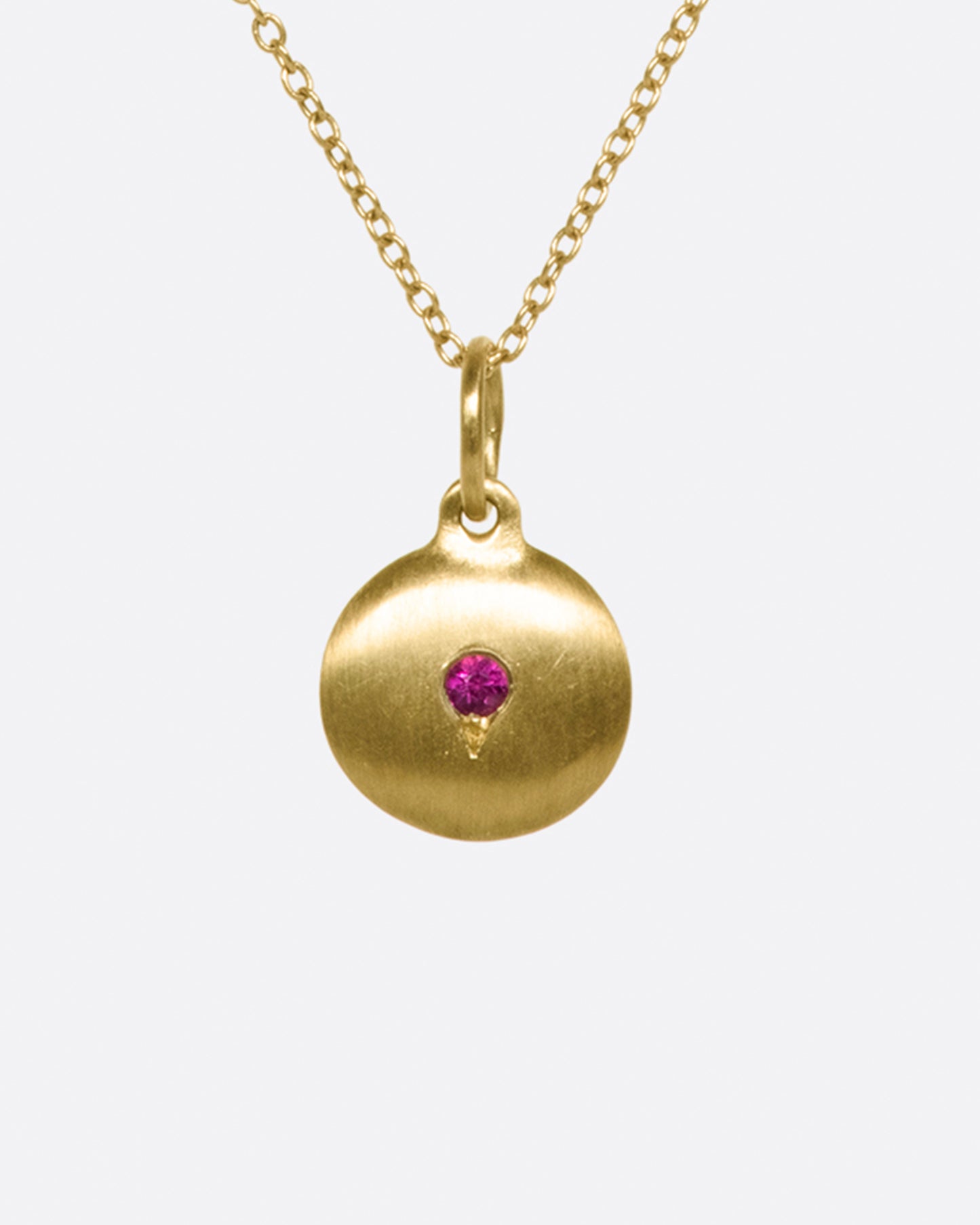 Layer this brushed gold medallion necklace with your favorite pieces; the ruby adds a little pop of color.