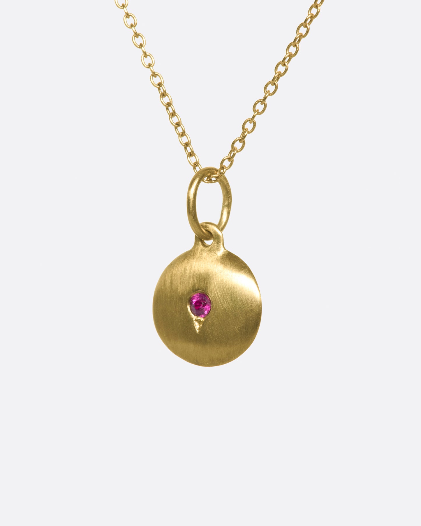 Layer this brushed gold medallion necklace with your favorite pieces; the ruby adds a little pop of color.