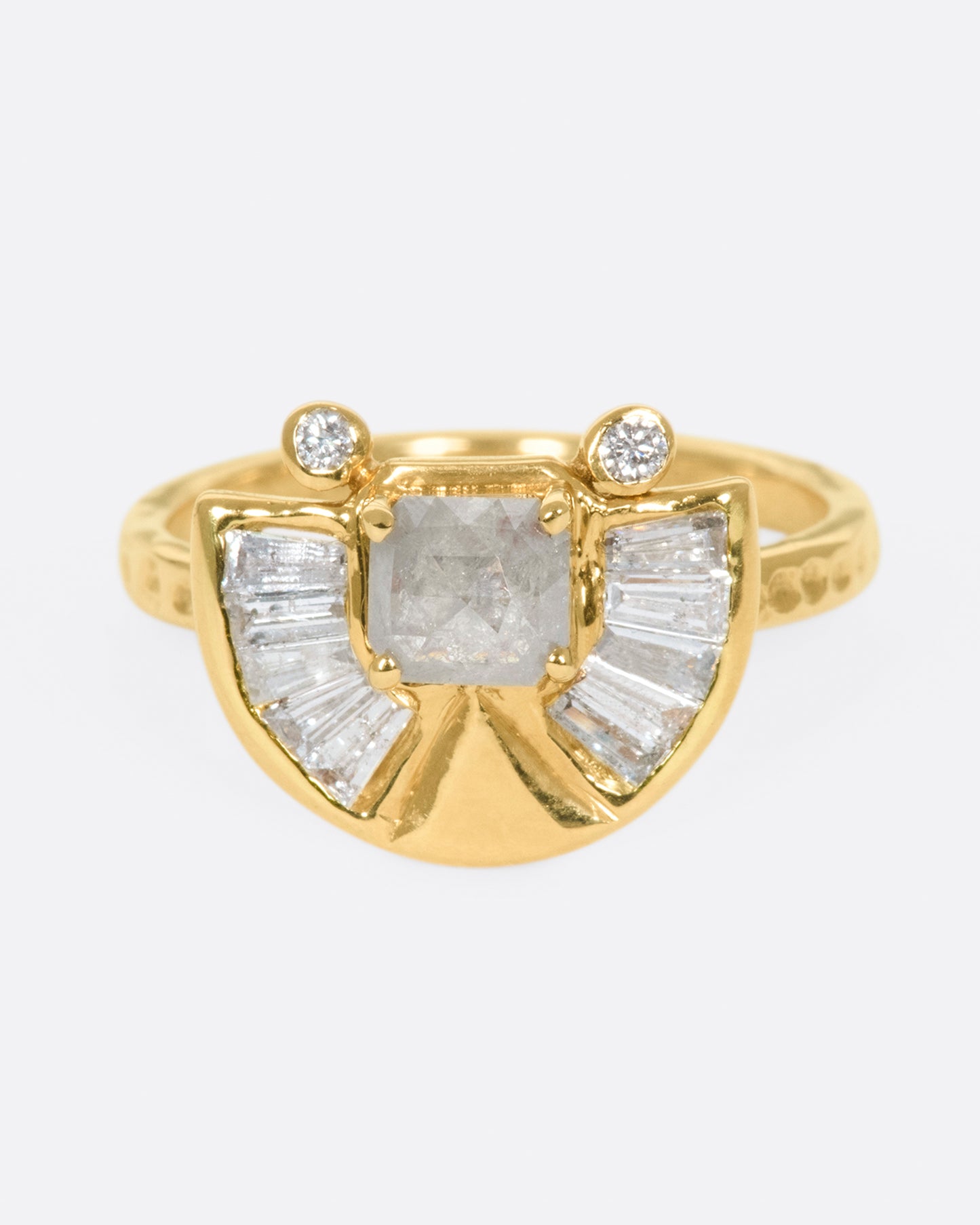 A textured gold ring with a rose cut salt & pepper diamond at its center surrounded by round and baguette diamond accents.