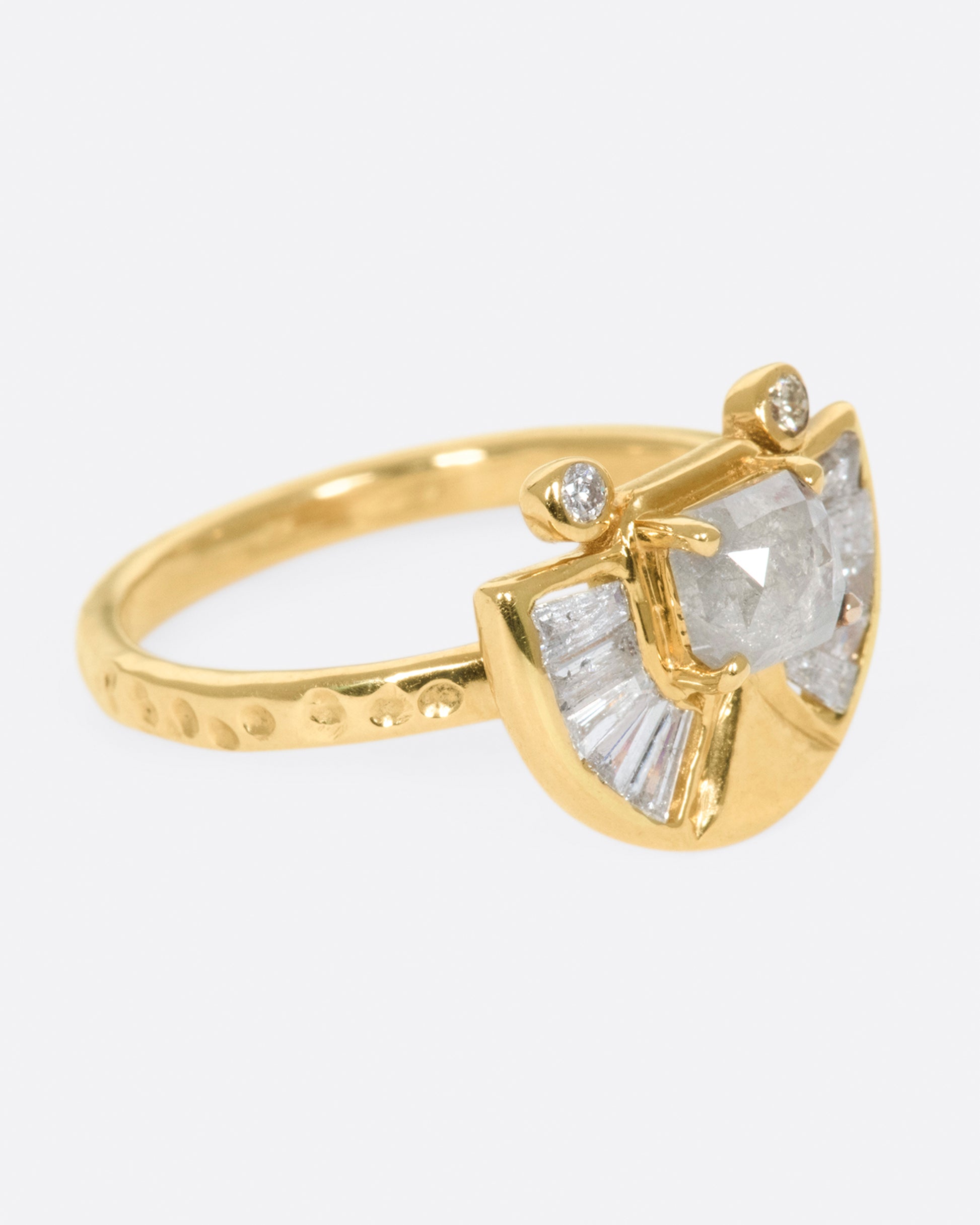 A textured gold ring with a rose cut salt & pepper diamond at its center surrounded by round and baguette diamond accents.