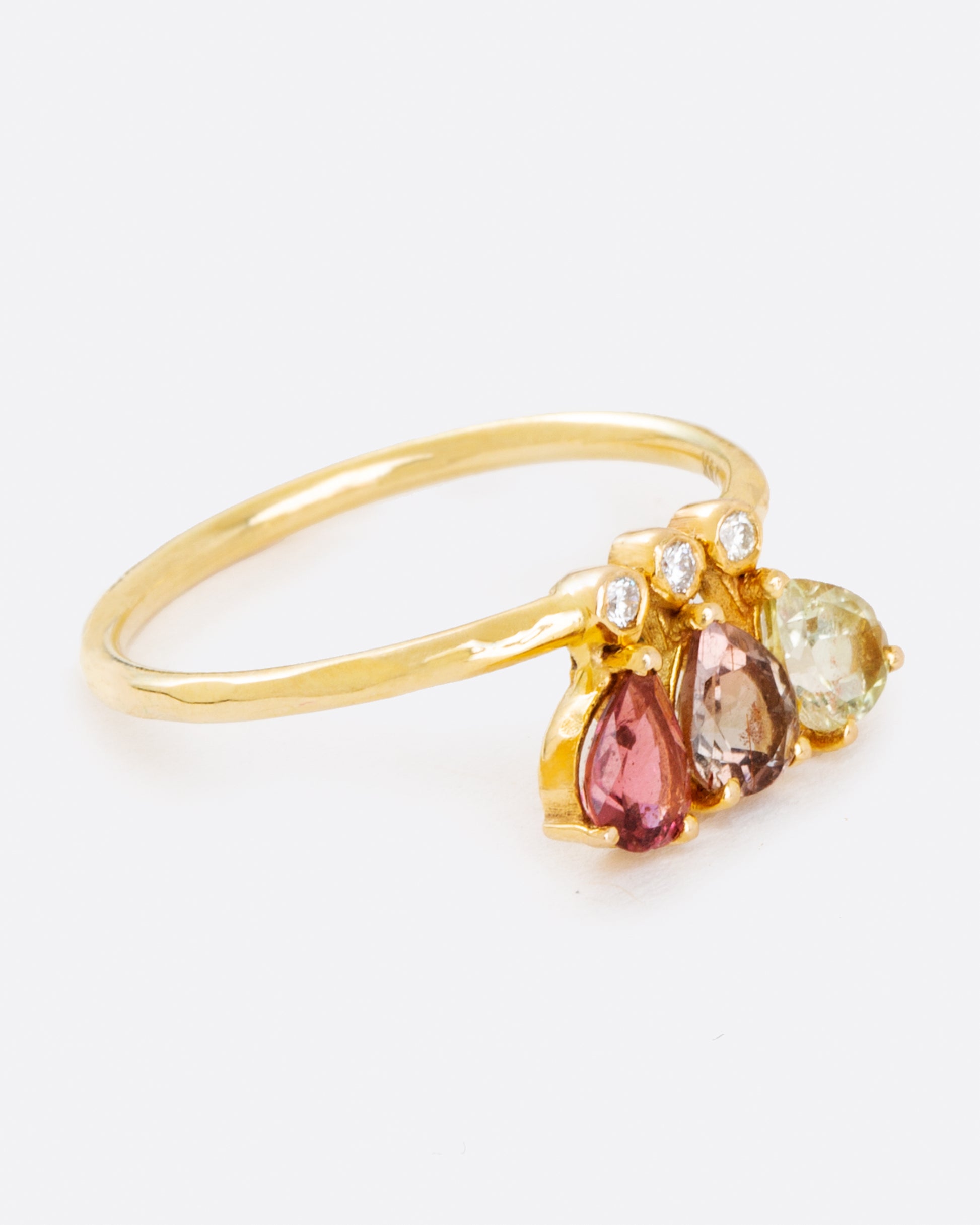 A crown of pear shaped green, red, and pink tourmalines leap from bezel set diamonds on a thin, solid 14 karat gold band.