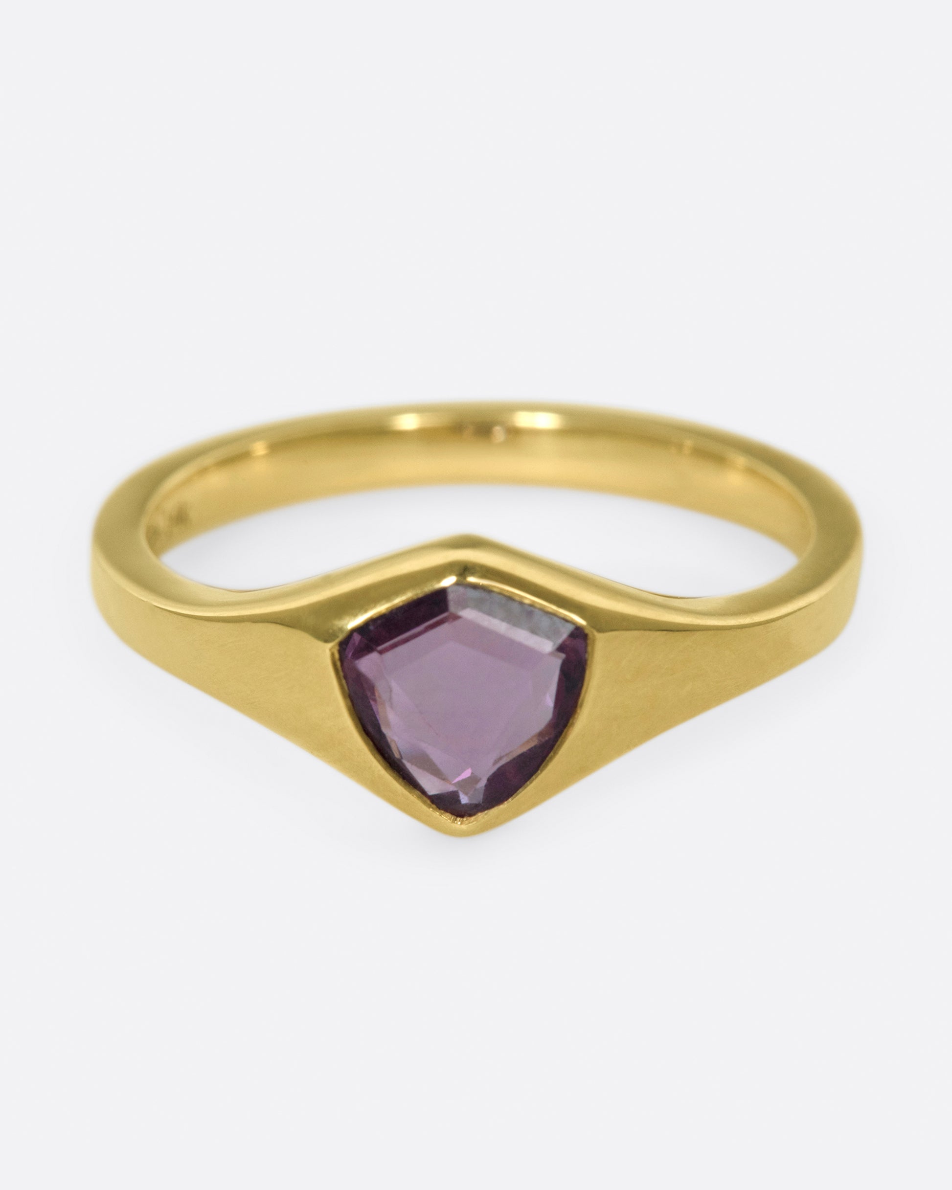 A classic, polished gold signet ring with a burgundy sapphire at its center.