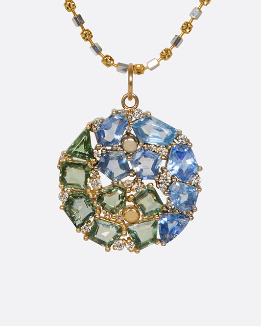 A two-tone yellow and white gold chain with a mosaic blue and green sapphire yin yang pendant.