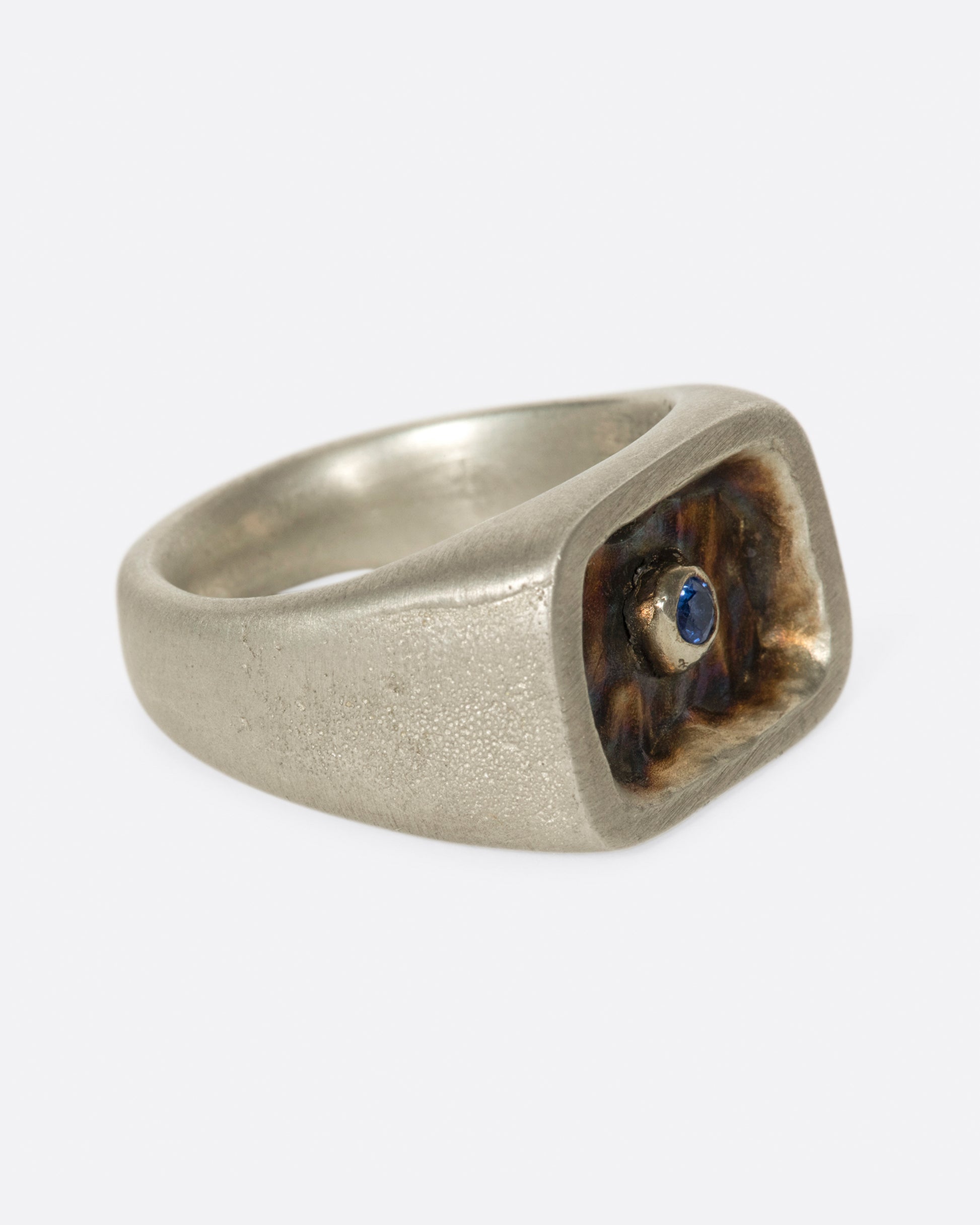 A solid, hand carved signet ring with gold plating and a royal blue sapphire.