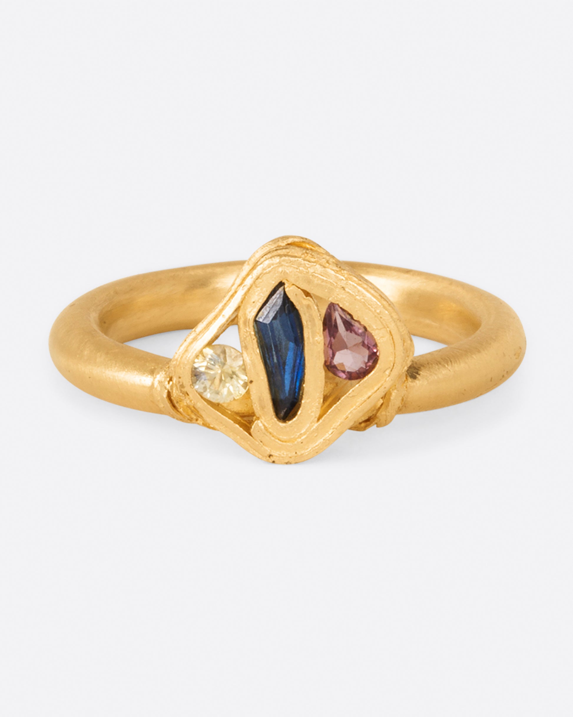 Three sapphires wrapped in yellow gold; one yellow, one pink, and one blue.