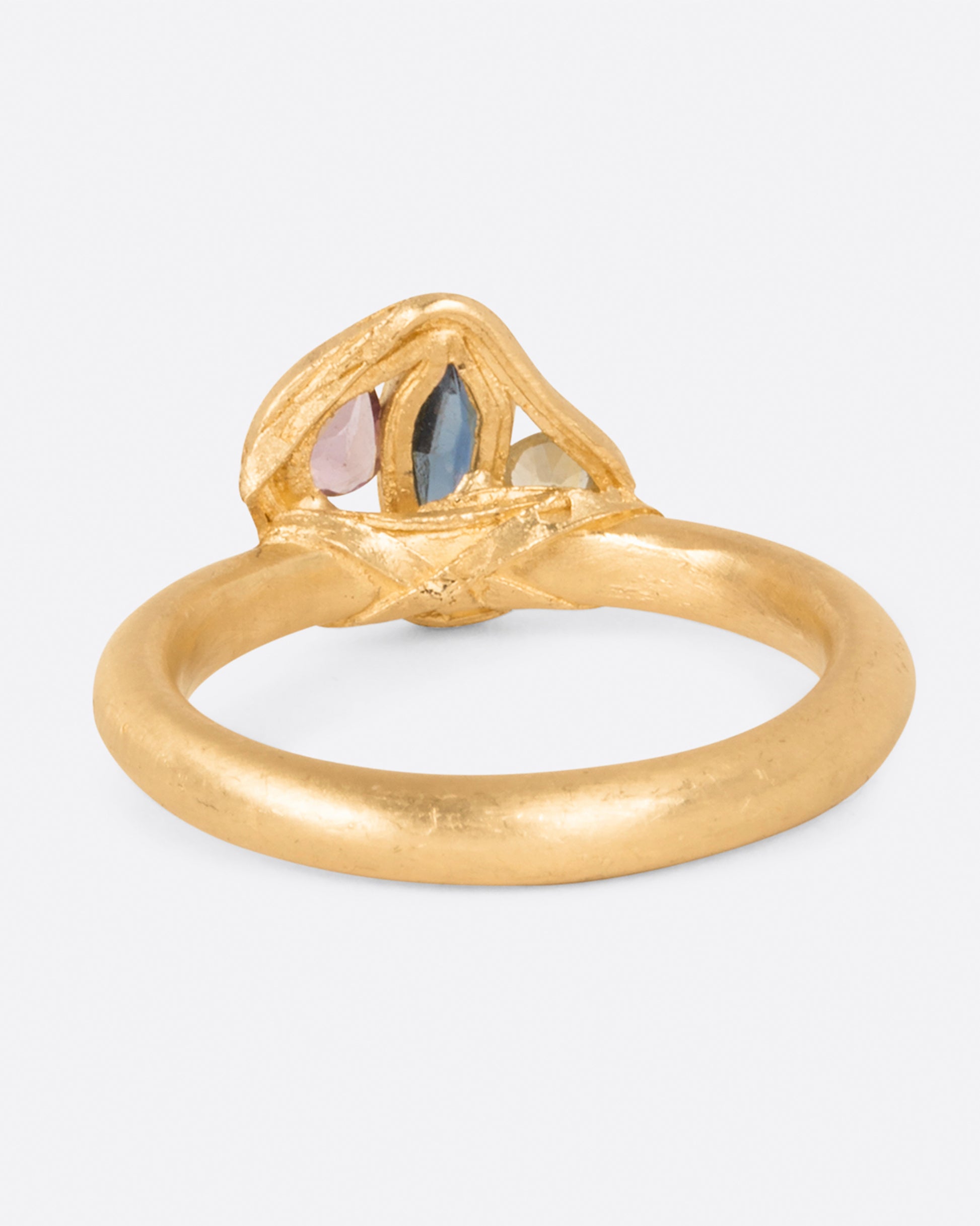 Three sapphires wrapped in yellow gold; one yellow, one pink, and one blue.