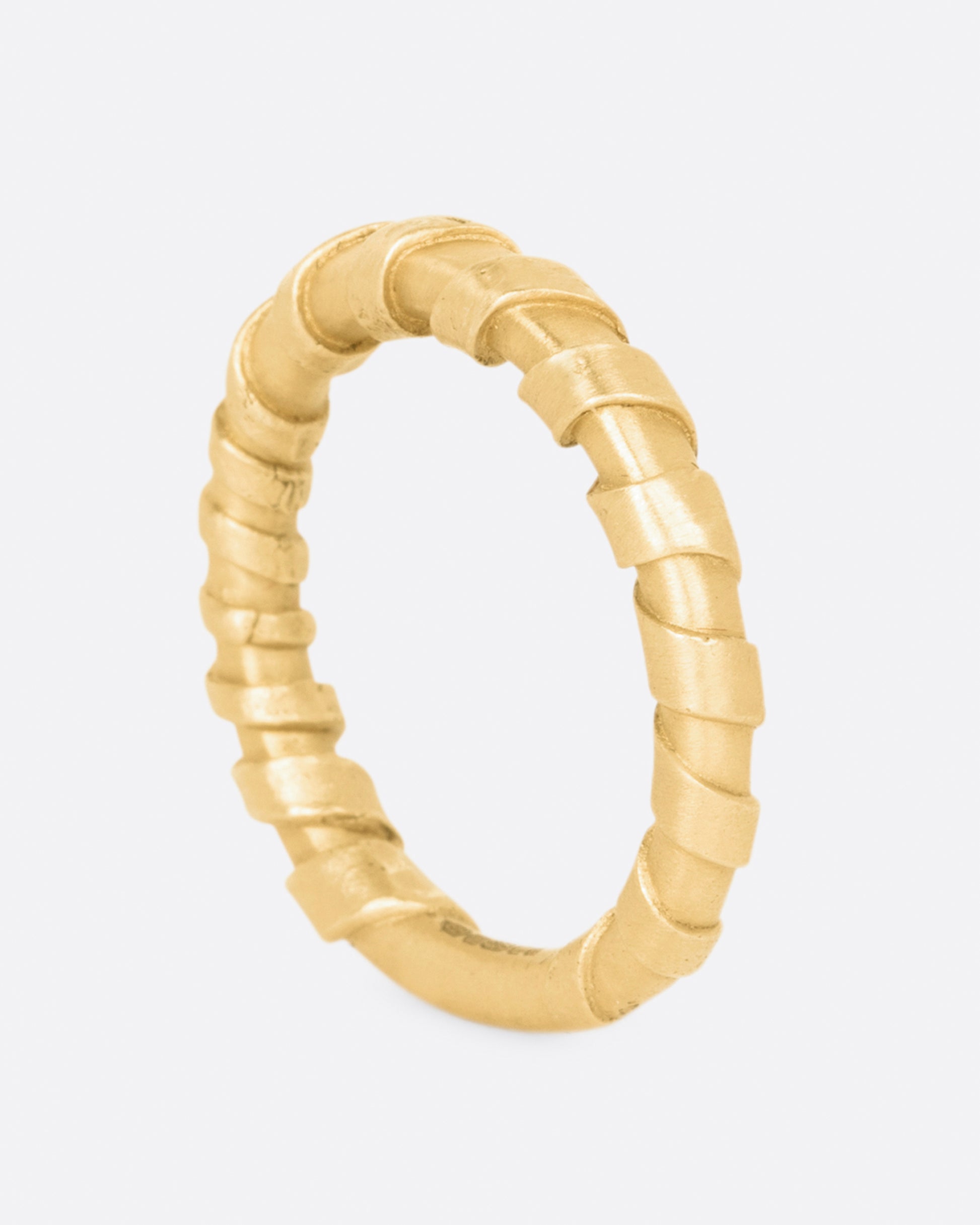 A rounded band, wrapped in a flat stripe of gold.