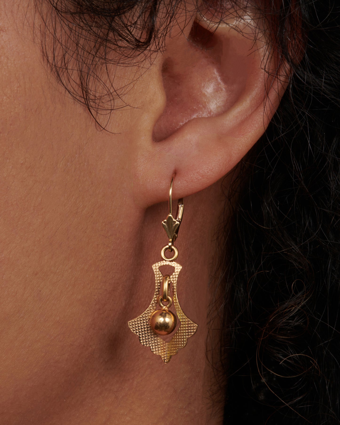 A pair of leverback earrings whose drops have great motion and sparkle just enough in the sun. View on an ear.