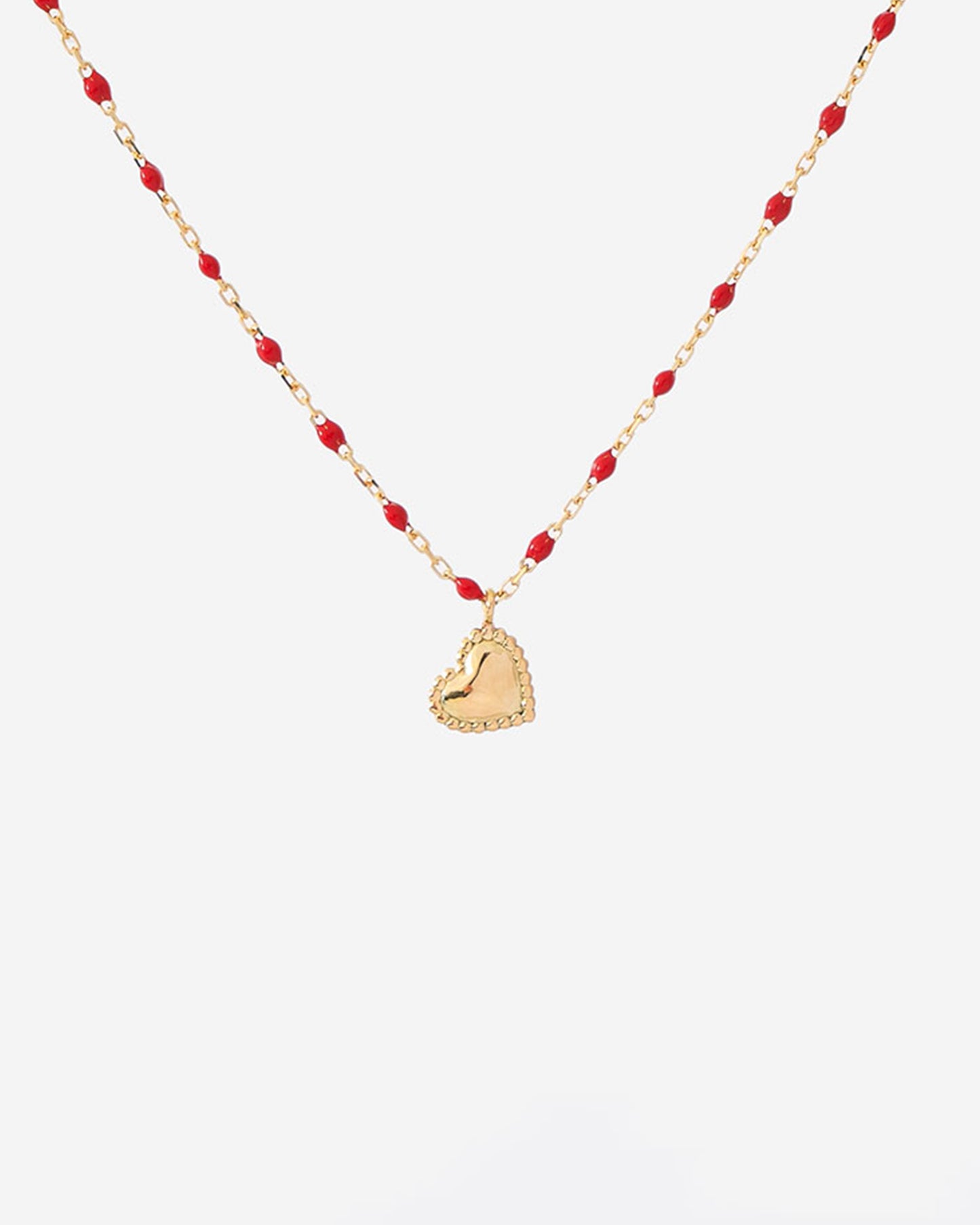 A thin yellow gold chain necklace with mini poppy red resin beads and a little dangling heart pendant.