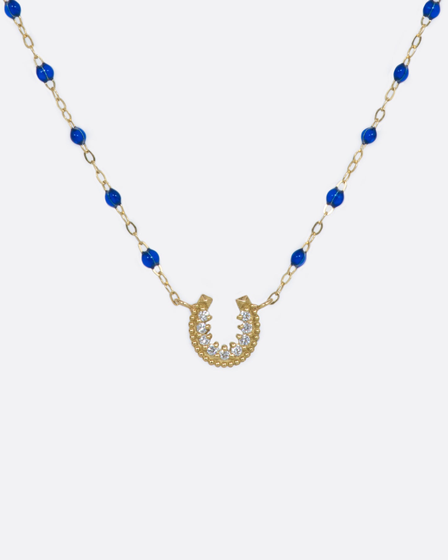 A yellow gold chain adorned with lapis blue resin beads and a lucky horseshoe pendant, lined with diamonds.