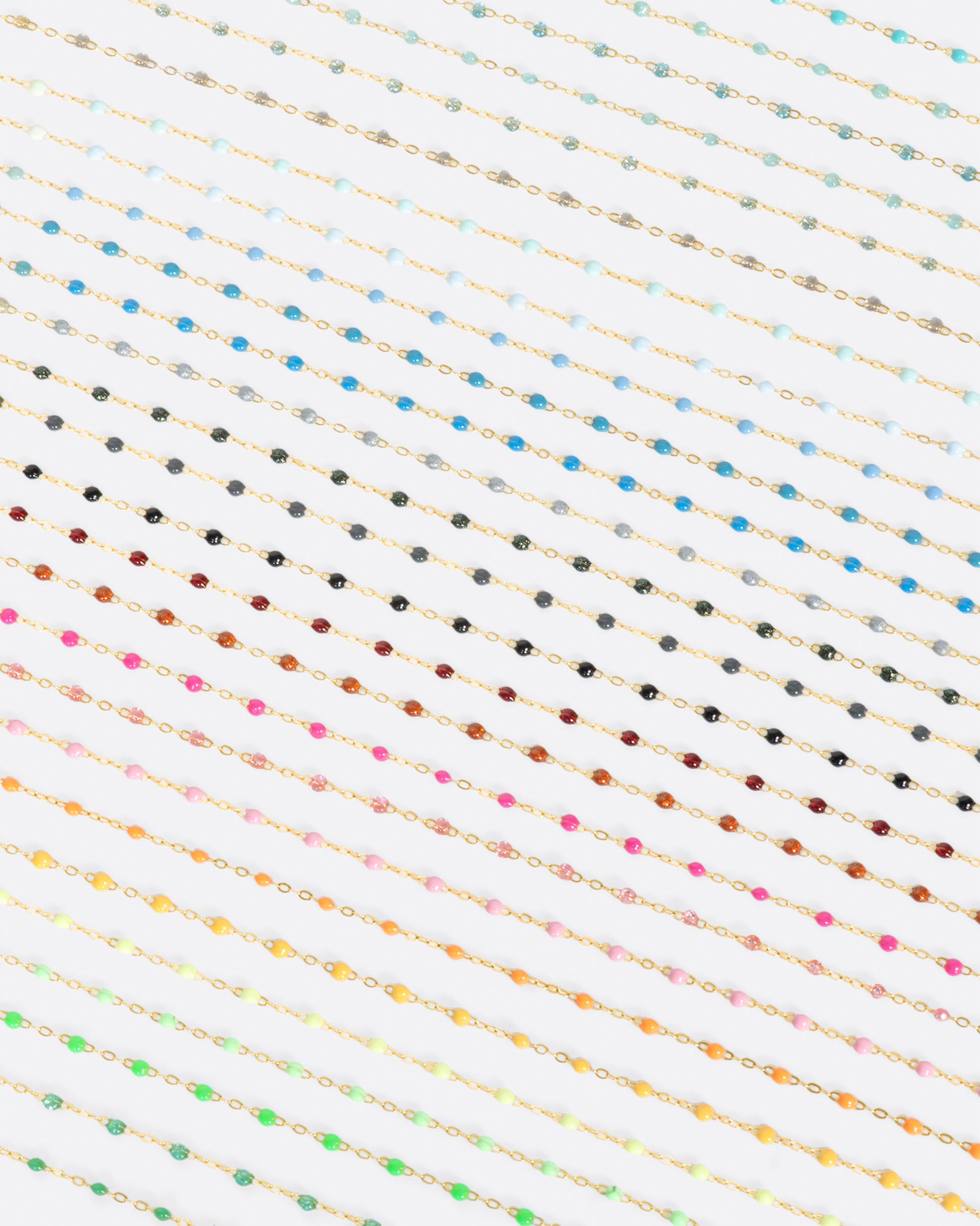 A photo of numerous yellow gold chains with different colors of resin beads.