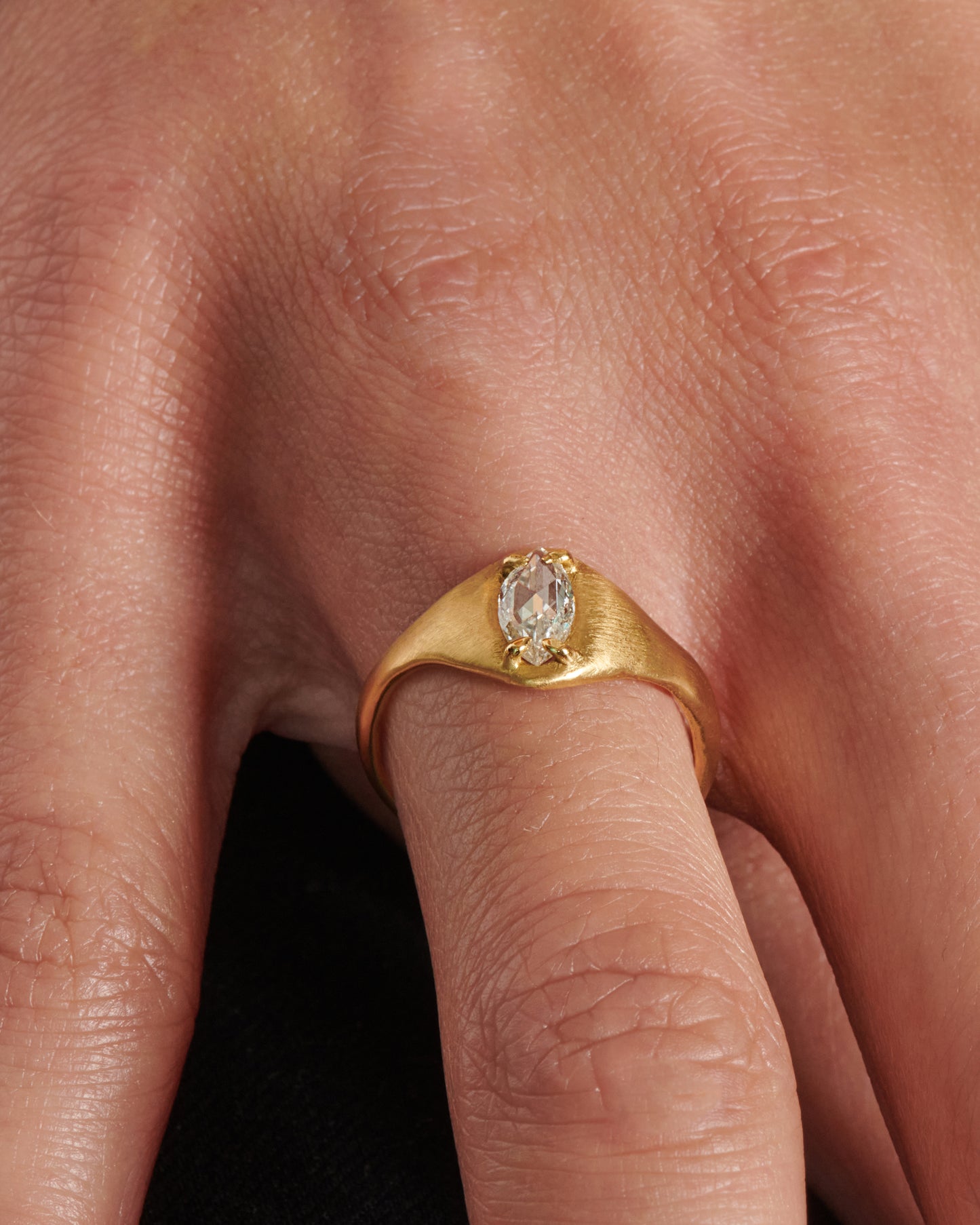 A prong set rose cut marquise diamond sits atop this satin-finish signet ring.