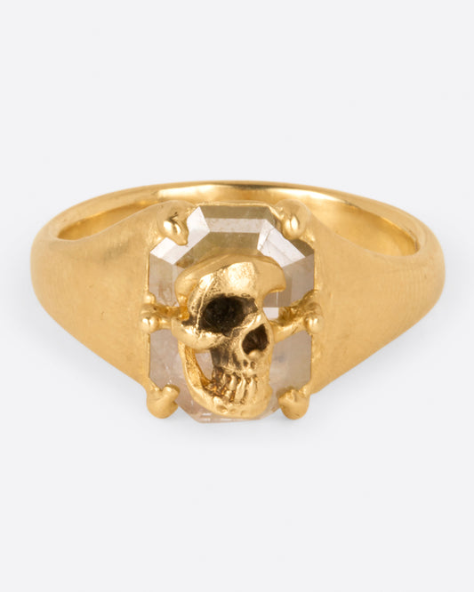 A hand carved skull pushes its way to the surface of a rose cut diamond on this one of a kind ring.