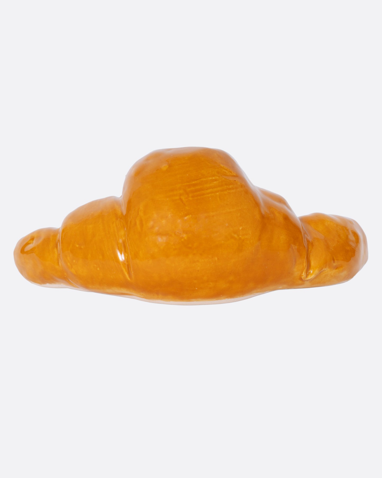 A croissant shaped candle holder with a candle in it, shown from the back.