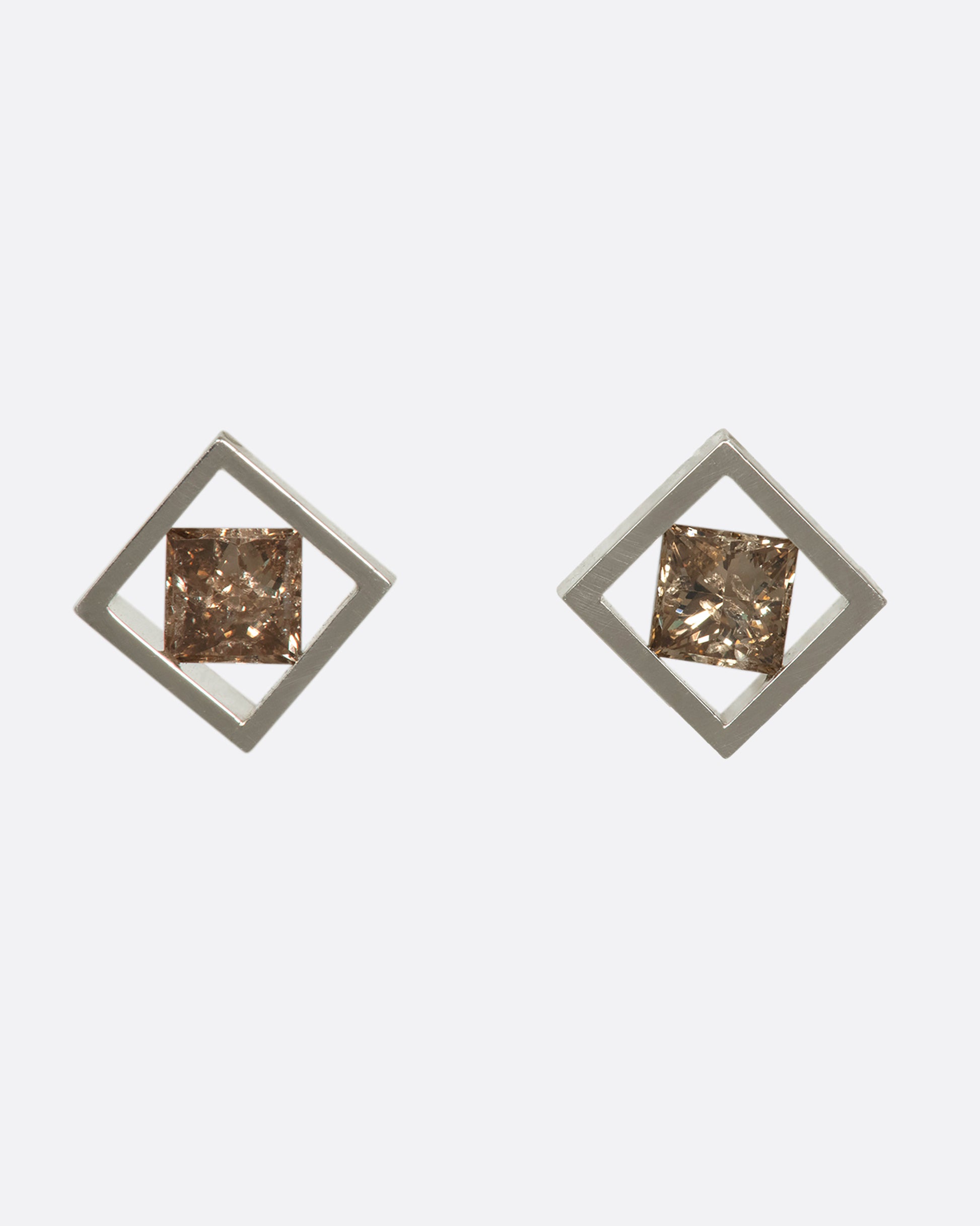 A pair of princess-cut cognac diamonds stretching across a square platinum setting