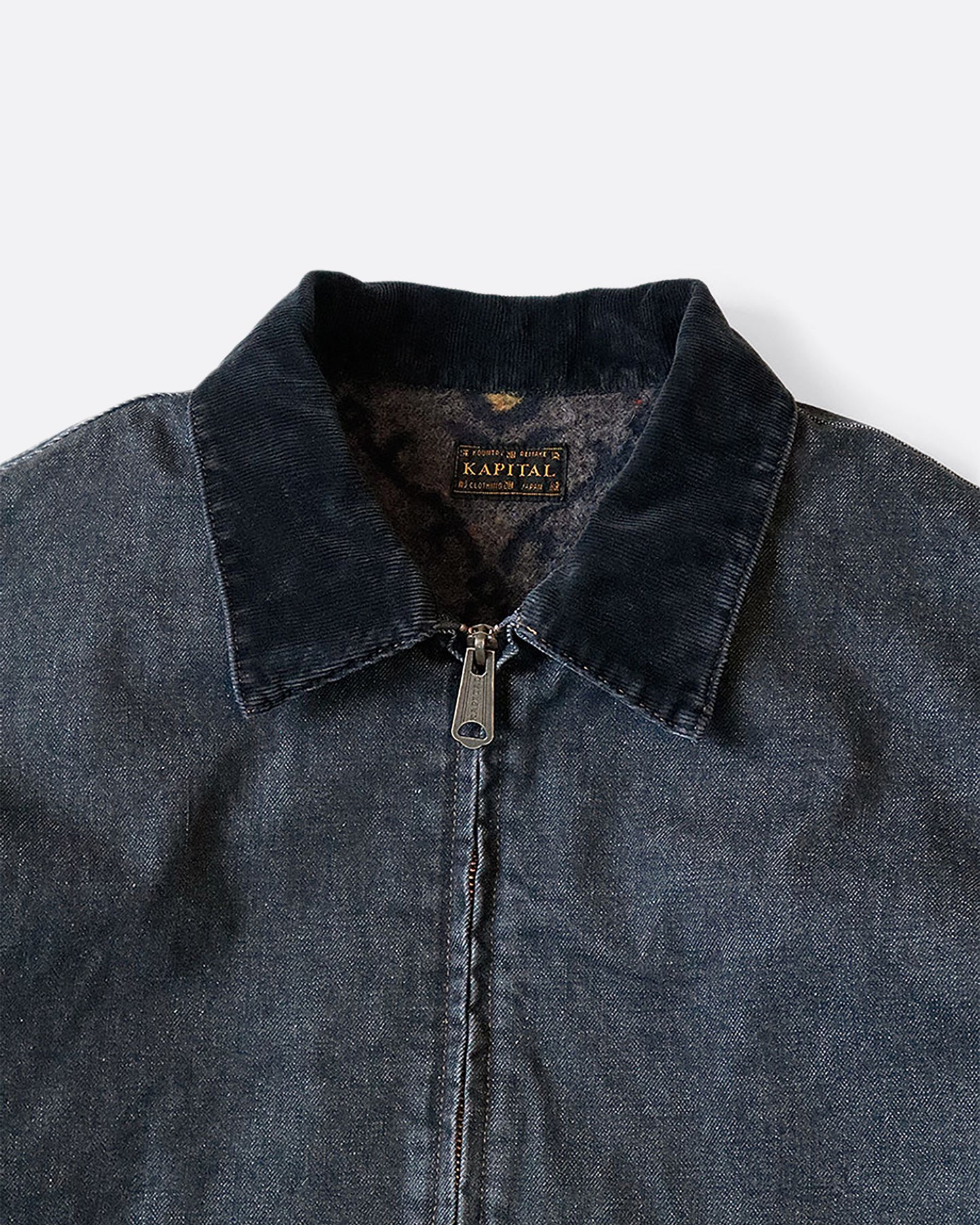 A dark blue denim bomber jacket with a corduroy collar and two front pockets. Close up view of the collar.