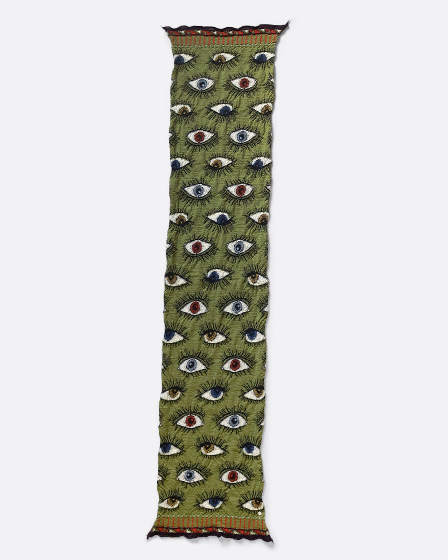 A green compressed wool scarf with an all- over eye pattern, shown open lying flat.