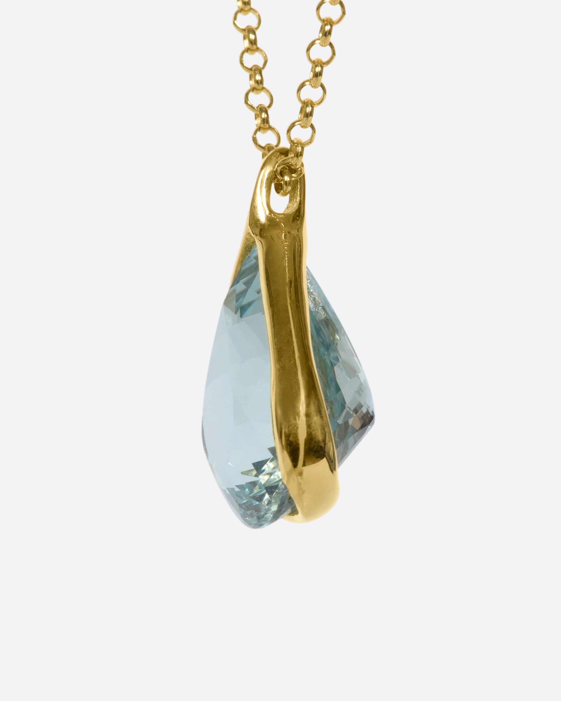 A yellow gold cable chain necklace with a large triangular aquamarine pendant