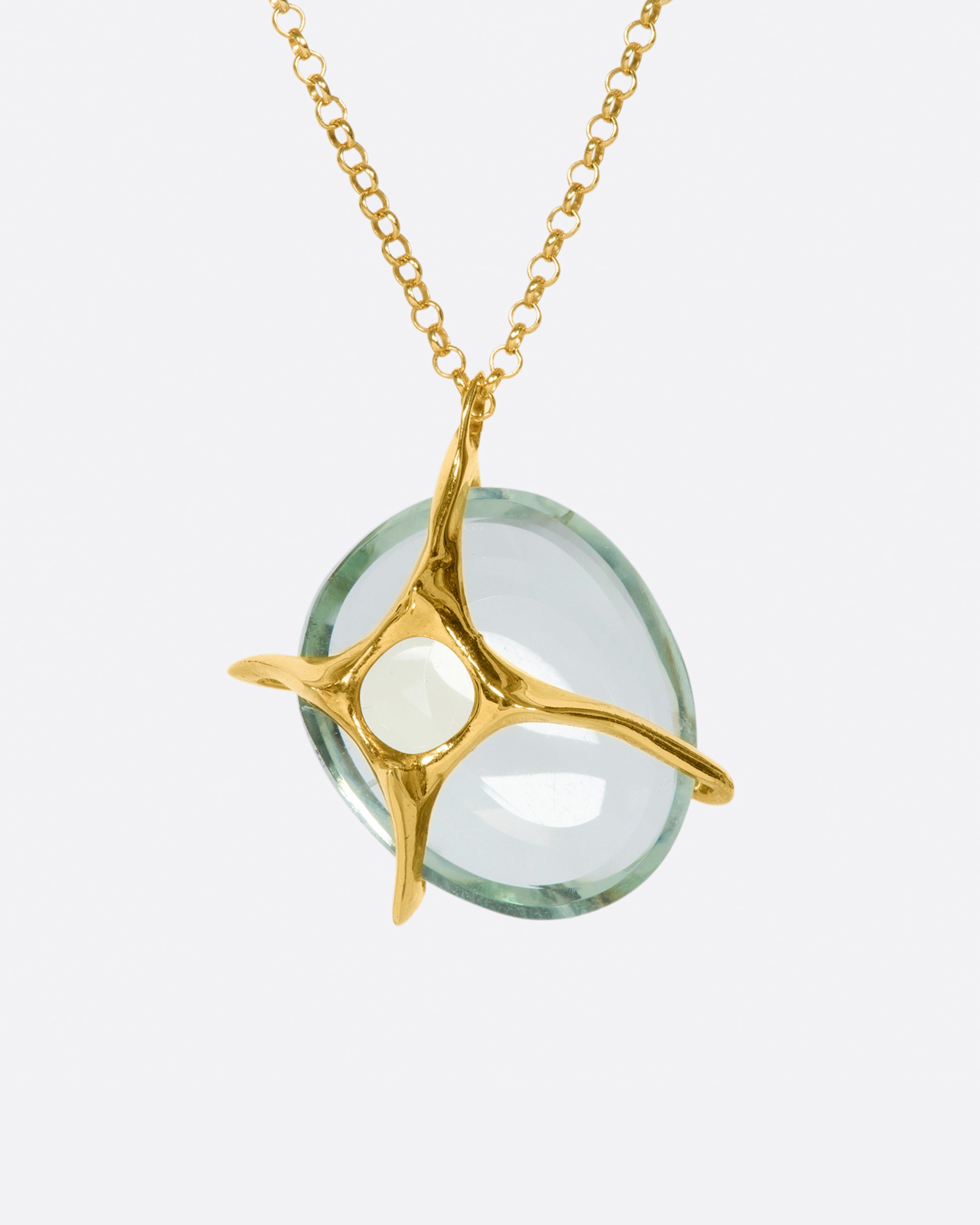 A yellow gold chain necklace with a large, round green quartz pendant set in large gold prongs.