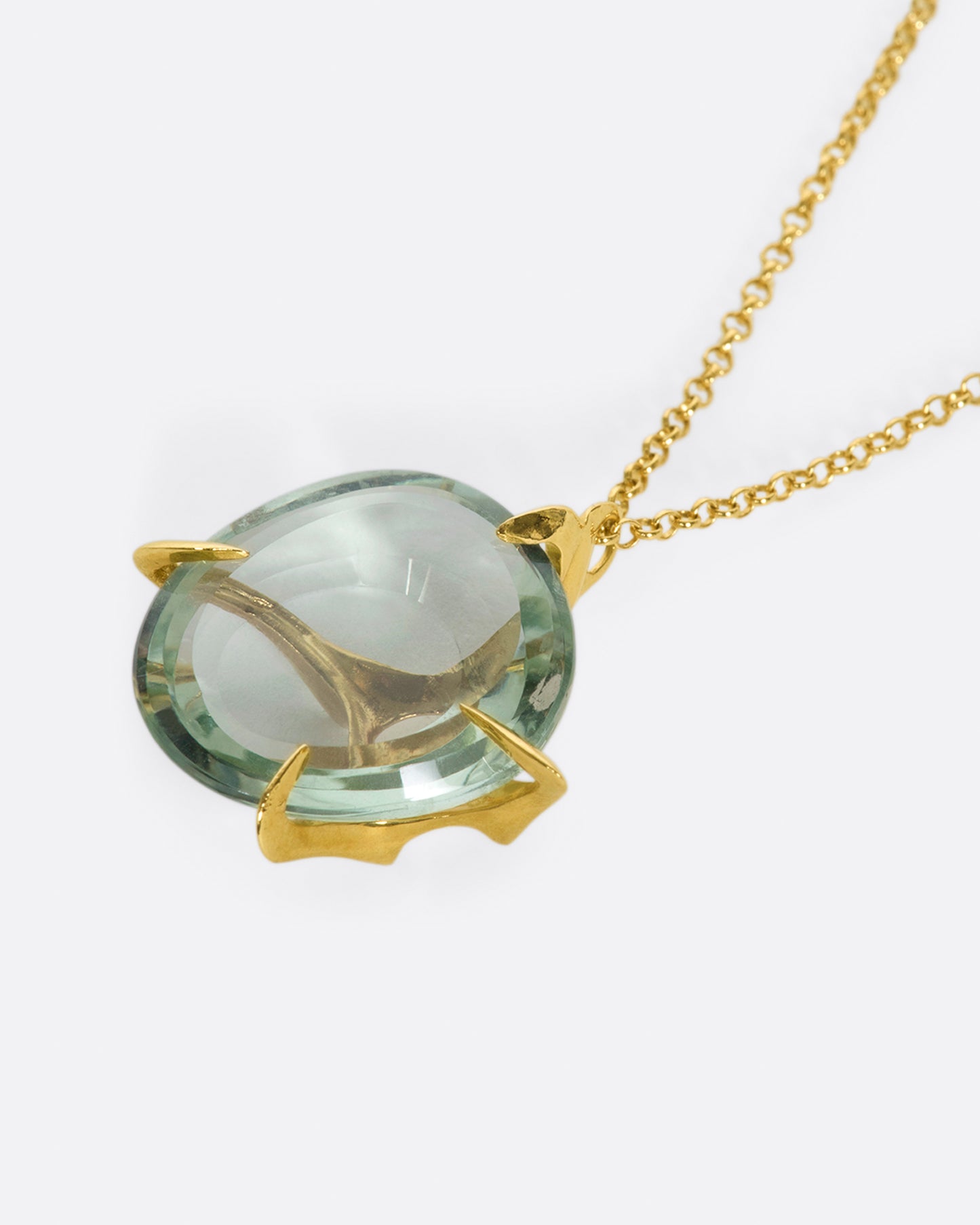 A yellow gold chain necklace with a large, round green quartz pendant set in large gold prongs.
