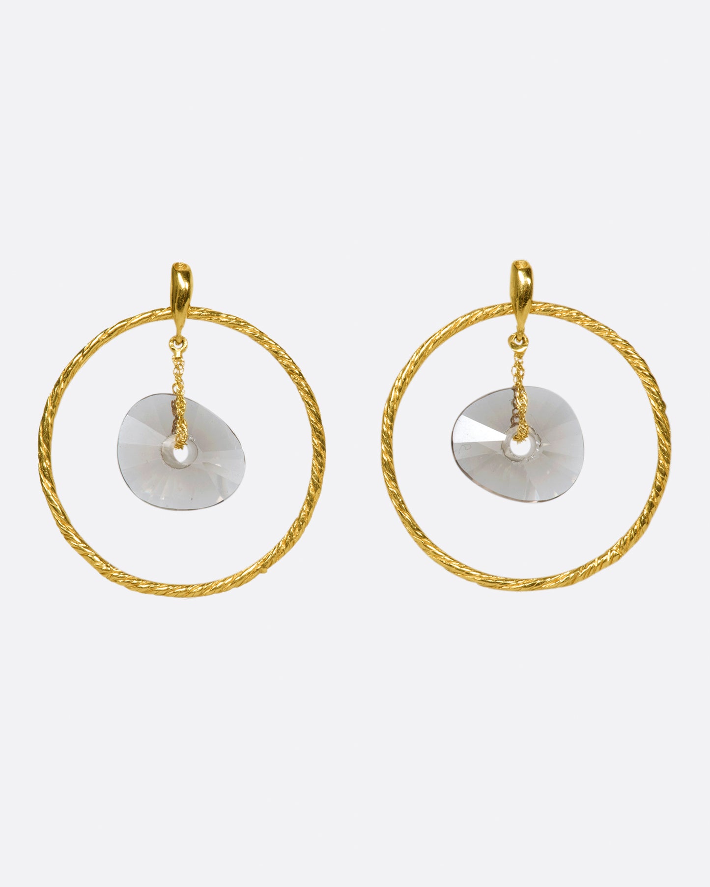 A pair of circular yellow gold wire earrings with smokey quartz donut-shaped beads hanging freely in the middle.