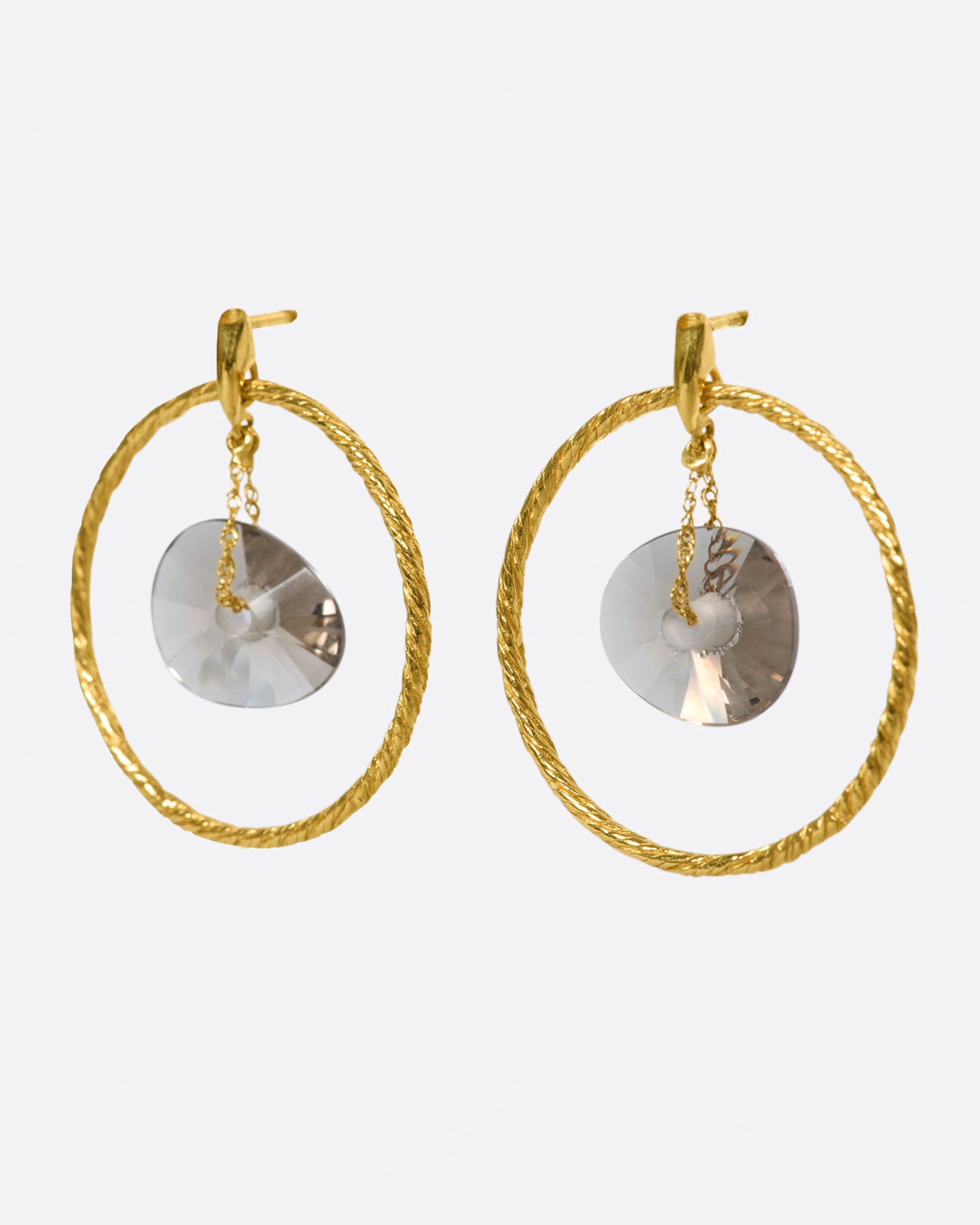 A pair of circular yellow gold wire earrings with smokey quartz donut-shaped beads hanging freely in the middle, shown from the side.