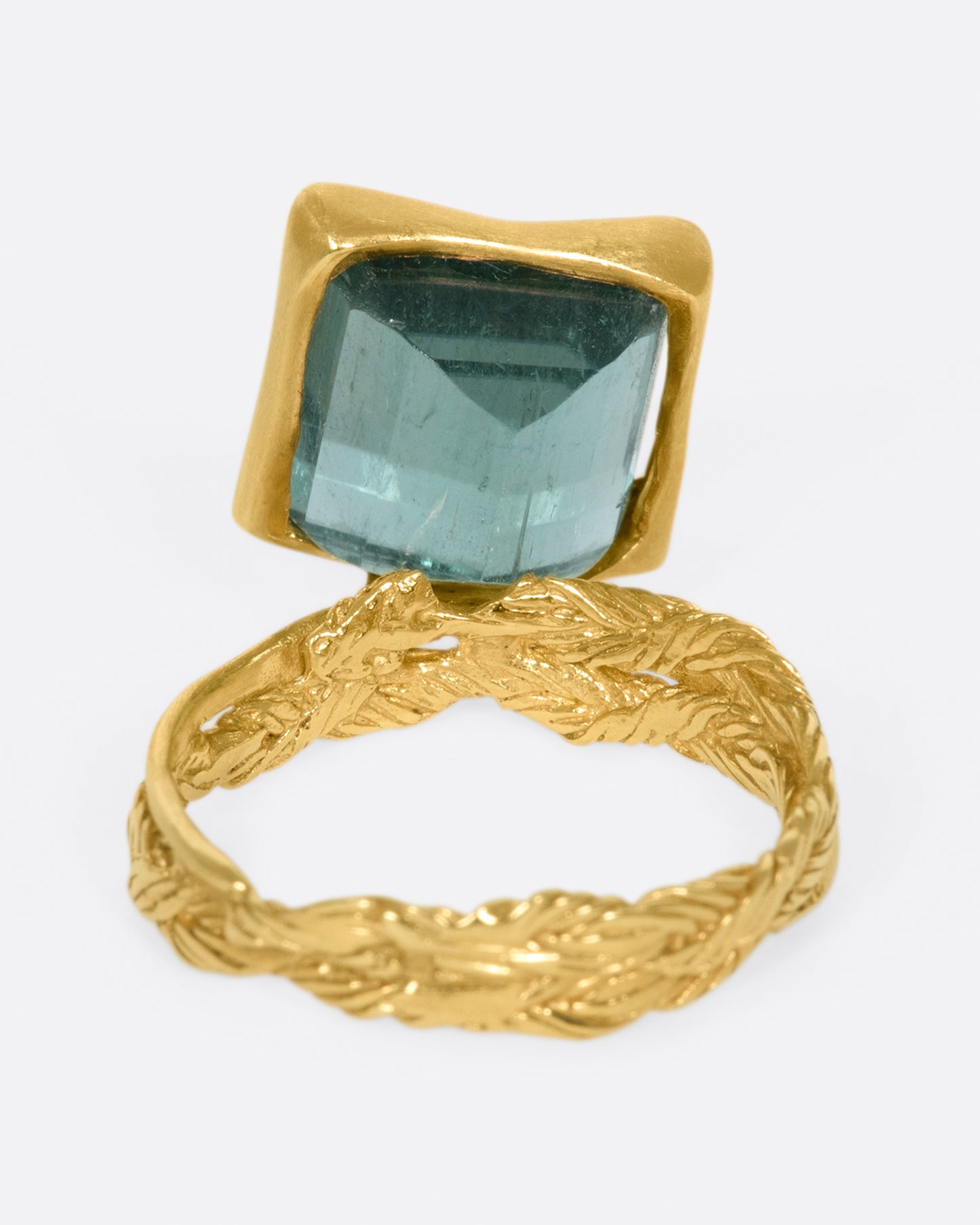 A gold braided band with a pale green square tourmaline.