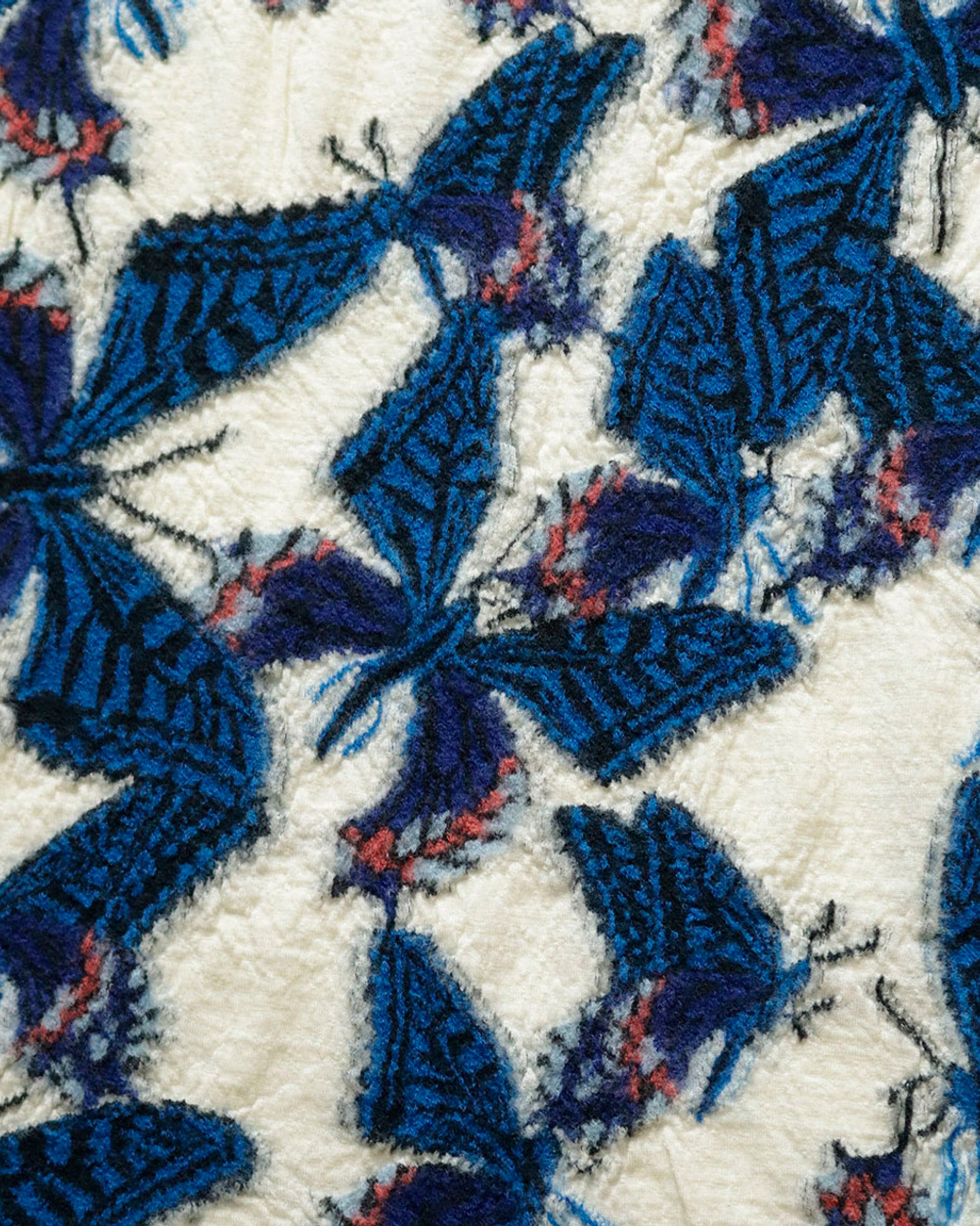 A close up of a white compressed wool scarf with blue butterflies all over it.