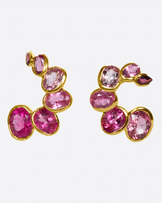 A pair of curved earrings with ombré pink tourmalines, shown from the front.
