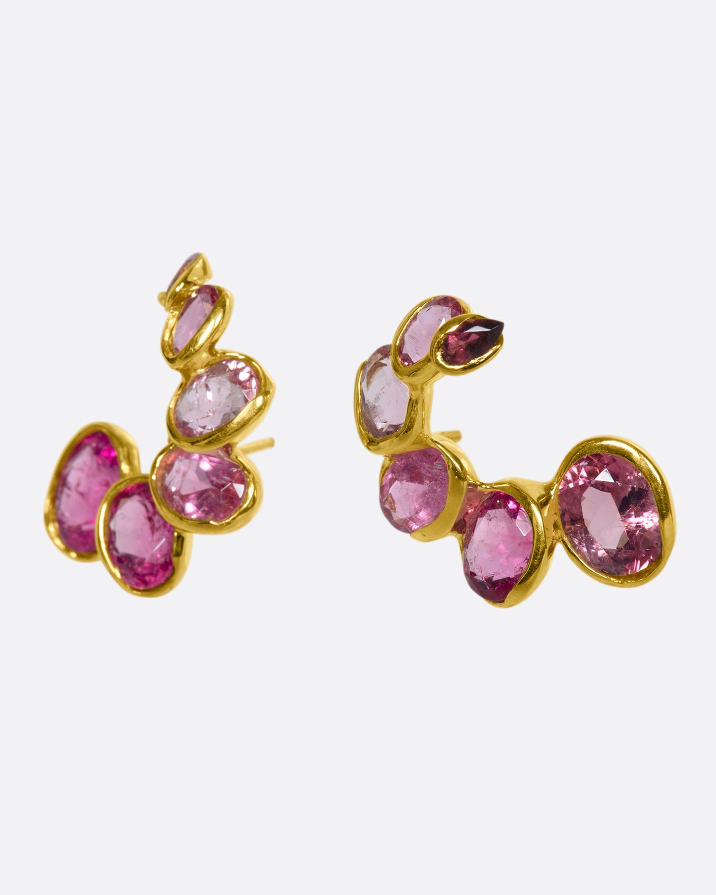 A pair of curved earrings with ombré pink tourmalines, shown from the side.