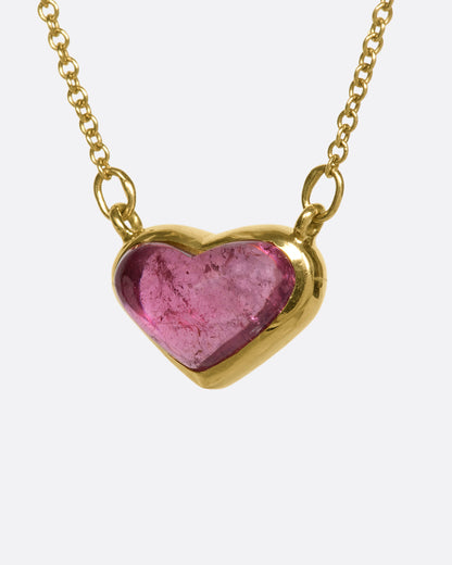 This 18k gold chain holds a unique watermelon rubellite heart encased in a gold bezel setting