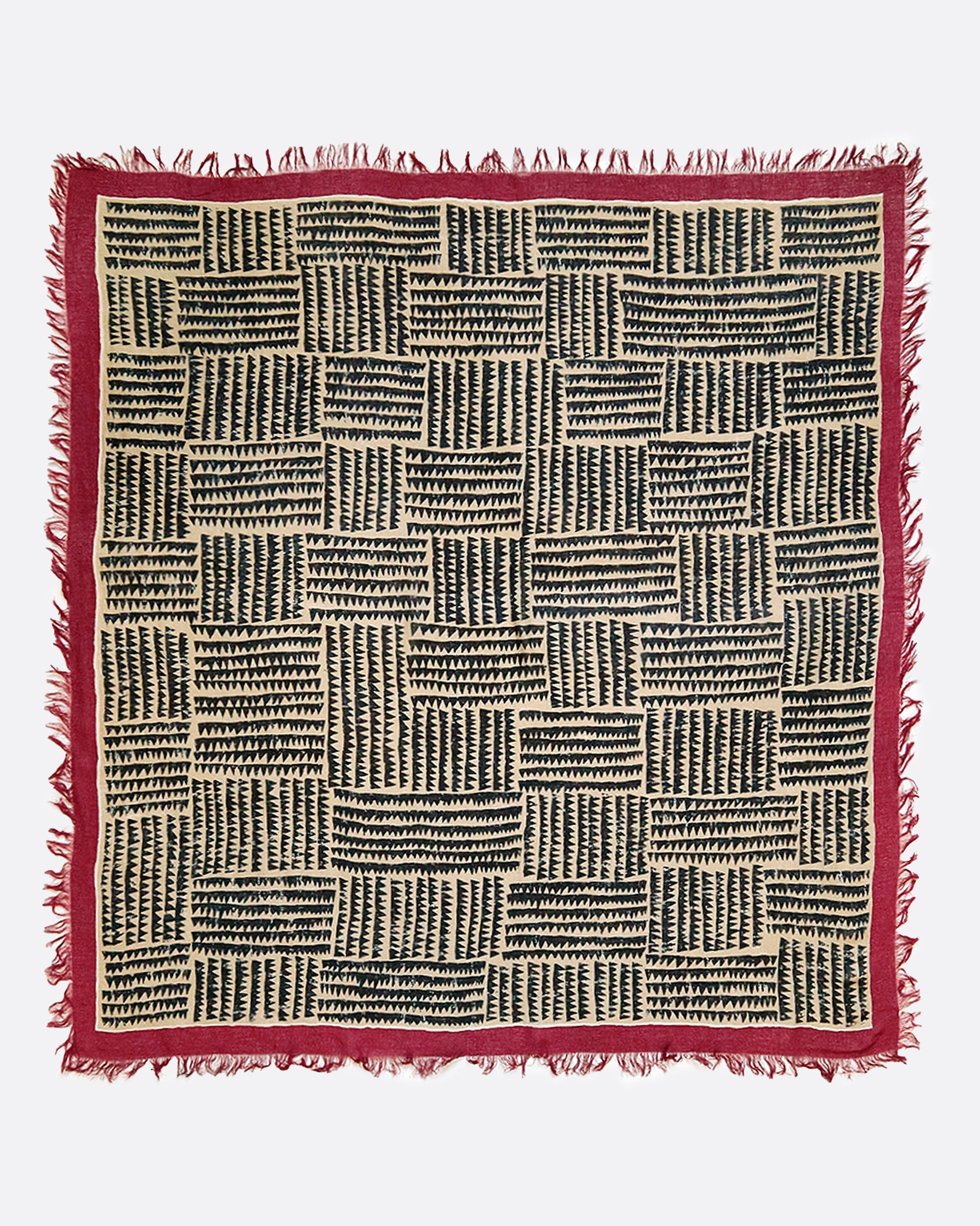 A large, fringy stole covered in a sawtooth block pattern with cranberry red edges.​