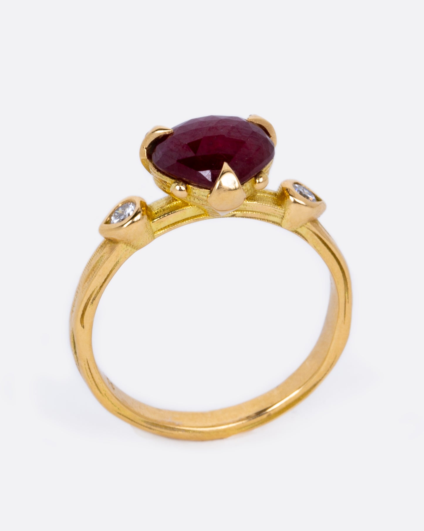 A deep red, rose cut ruby heart flanked by two white diamonds.