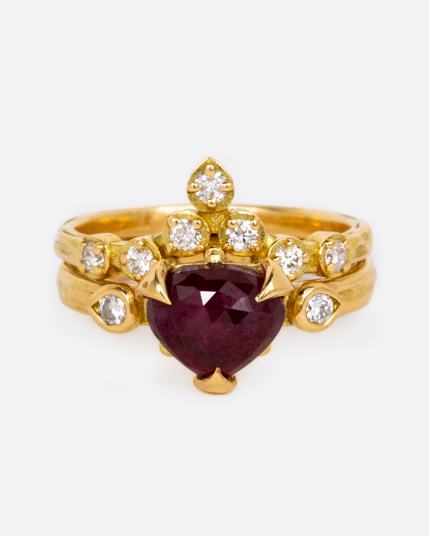 A deep red, rose cut ruby heart flanked by two white diamonds.