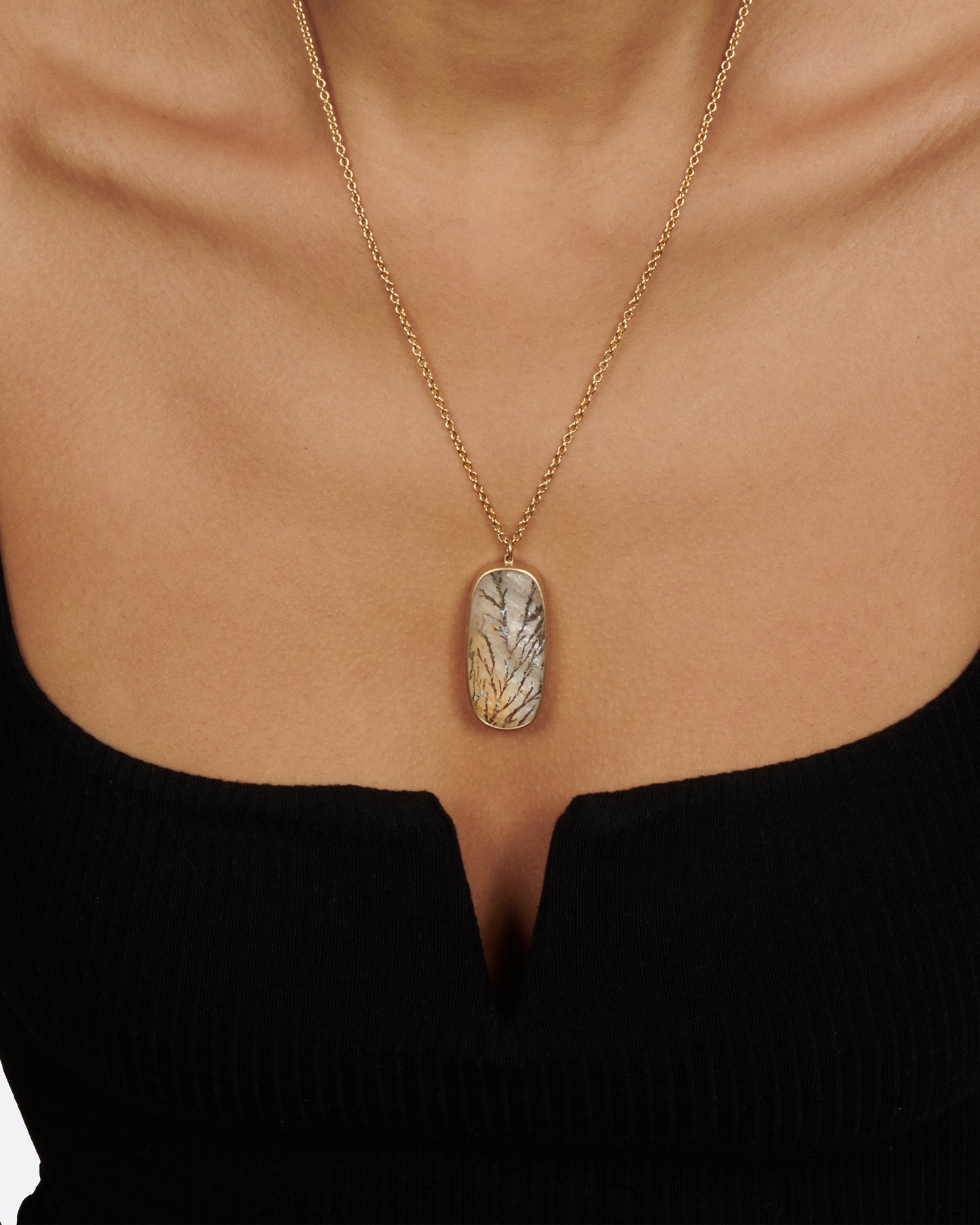 This oval dendritic quartz pendant has fern like iron strands growing throughout and a notable changing luster, known as chatoyance.