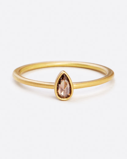 A yellow gold ring with a bezel set teardrop shaped diamond. Shown from the front.