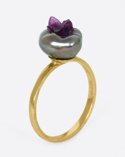 A yellow gold freshwater pearl ring lined with reclaimed rubies. View from the side standing up.