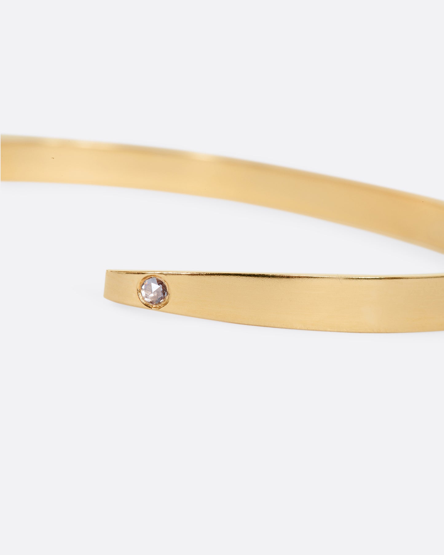 A yellow gold stripe bracelet with flush set rose cut diamond on the hook side. View of the diamond close up.