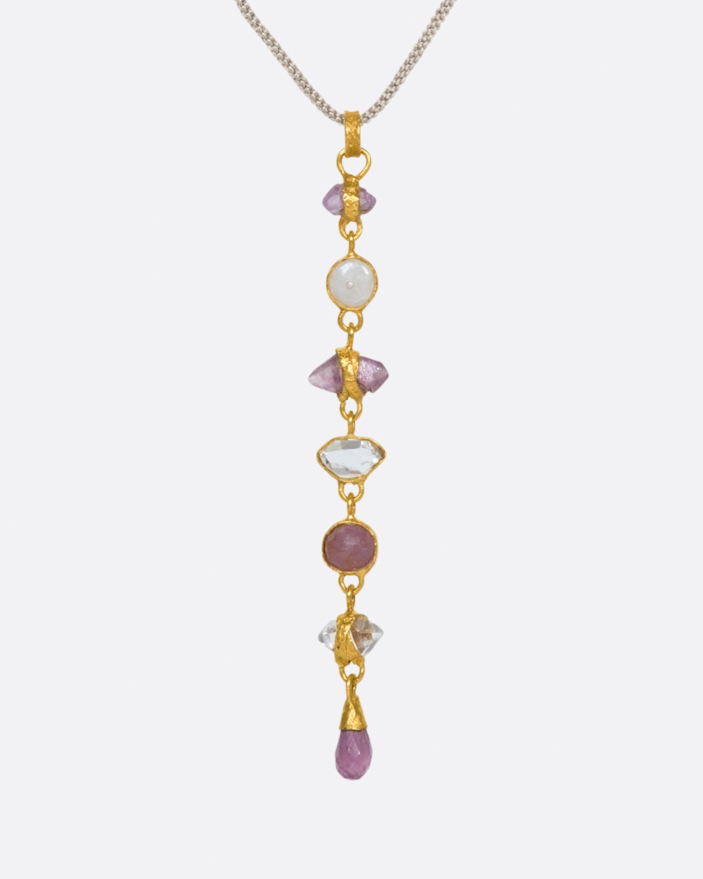 This high karat gold pendant features alternating rubies and herikmer diamonds with a matching pink sapphire drop at the bottom.