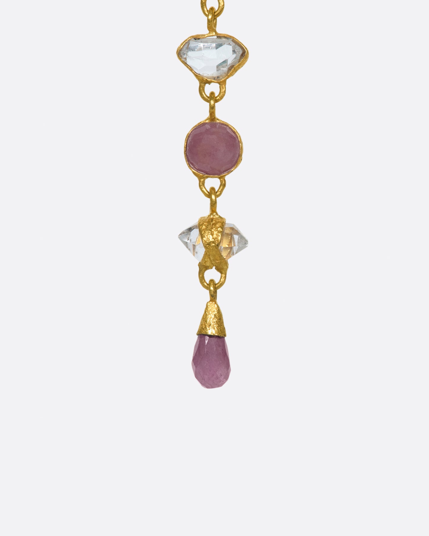 This high karat gold pendant features alternating rubies and herikmer diamonds with a matching pink sapphire drop at the bottom.
