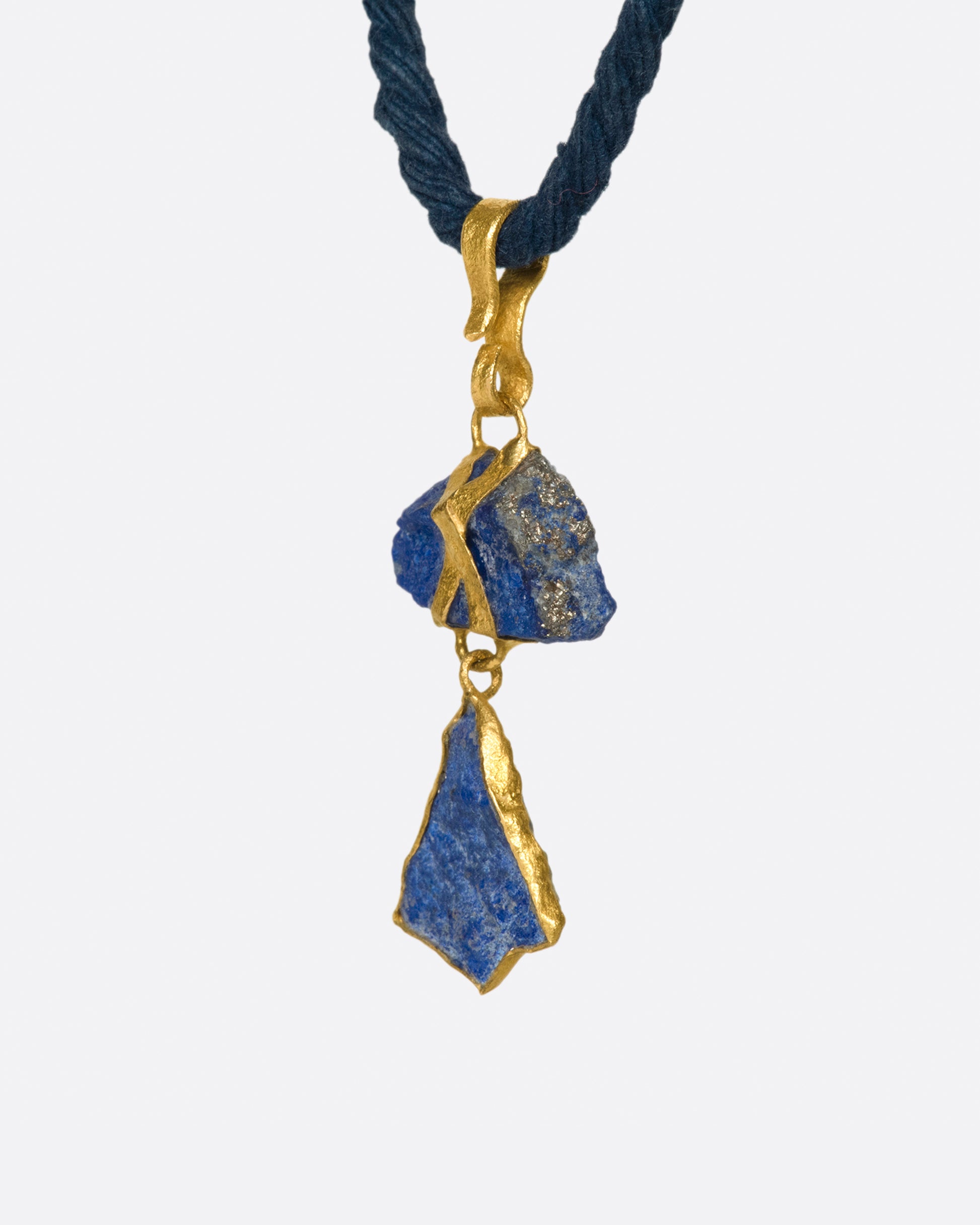 Two pieces of organic, untreated Afghan lapis wrapped in high karat gold, hanging on an adjustable blue cord.