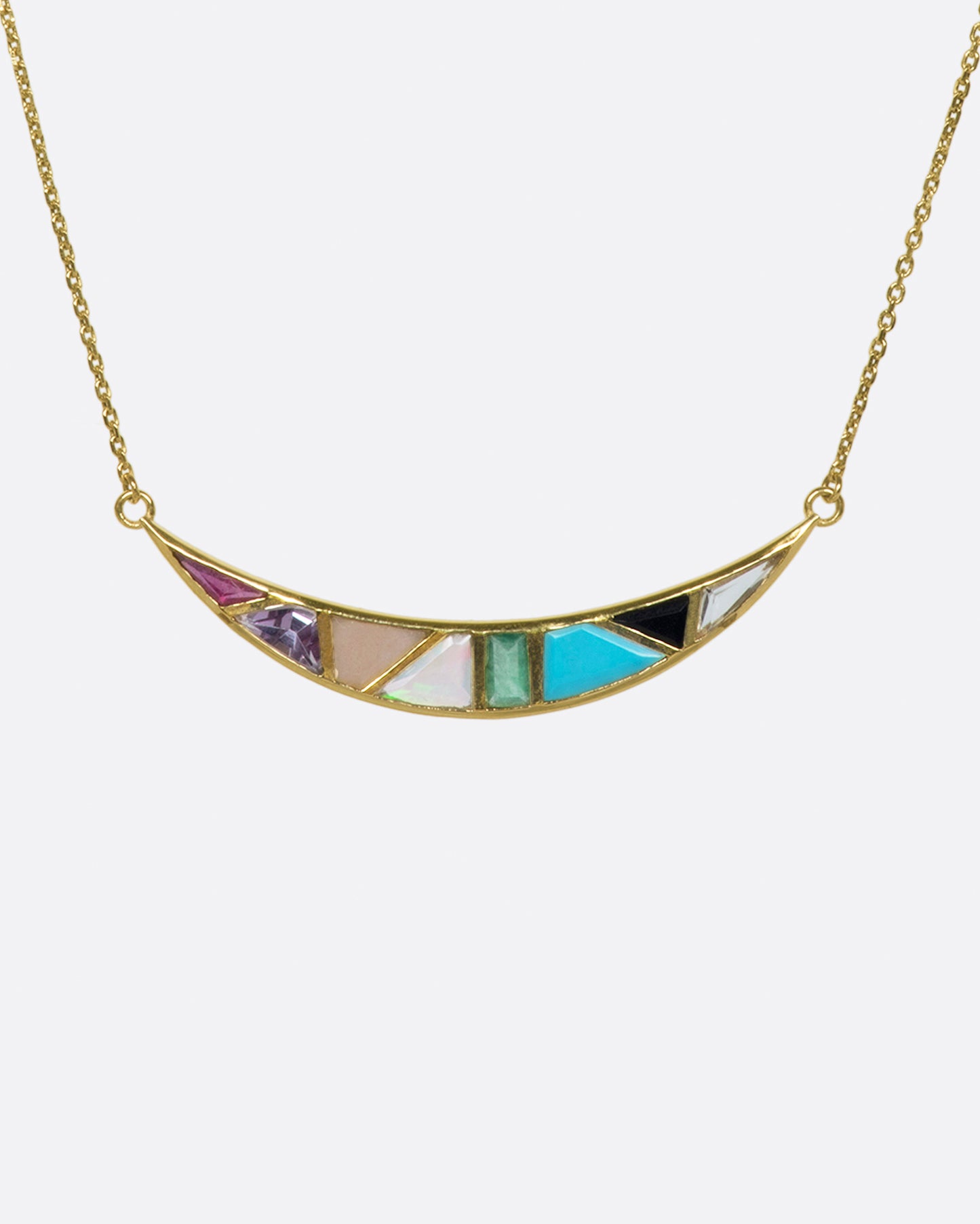 A crescent moon pendant necklace with a captivating mosaic of hand-cut stones.