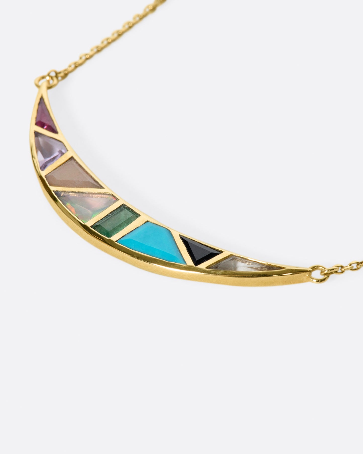 A crescent moon pendant necklace with a captivating mosaic of hand-cut stones.