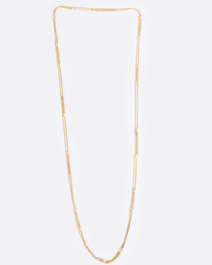 A long yellow gold multi chain necklace with alternating pattern of squares finished with gold solder. Shown from the front.