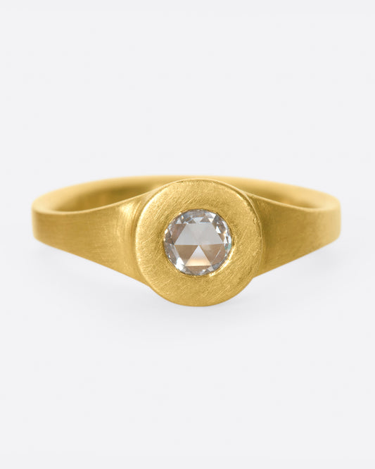 A rose cut diamond sits at the center of this hand carved, matte gold ring.