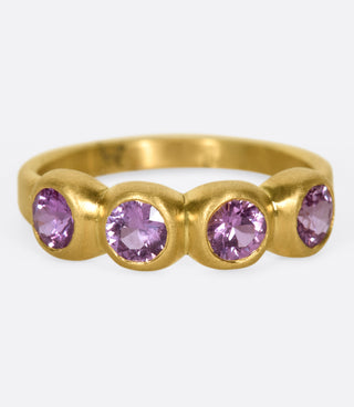 Four deep pink sapphire set in satin-finish bezels on a matte gold band.