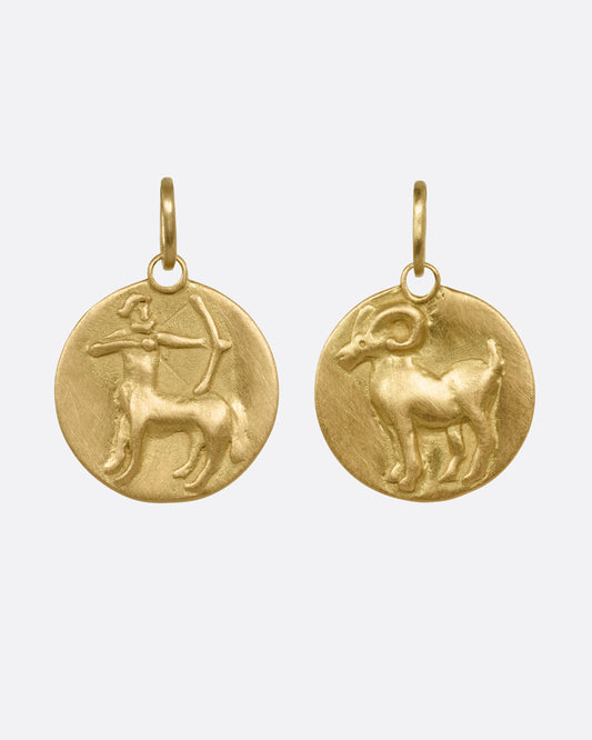 Two yellow gold circular zodiac pendants- one Aries, the other Sagittarius, shown from the front.