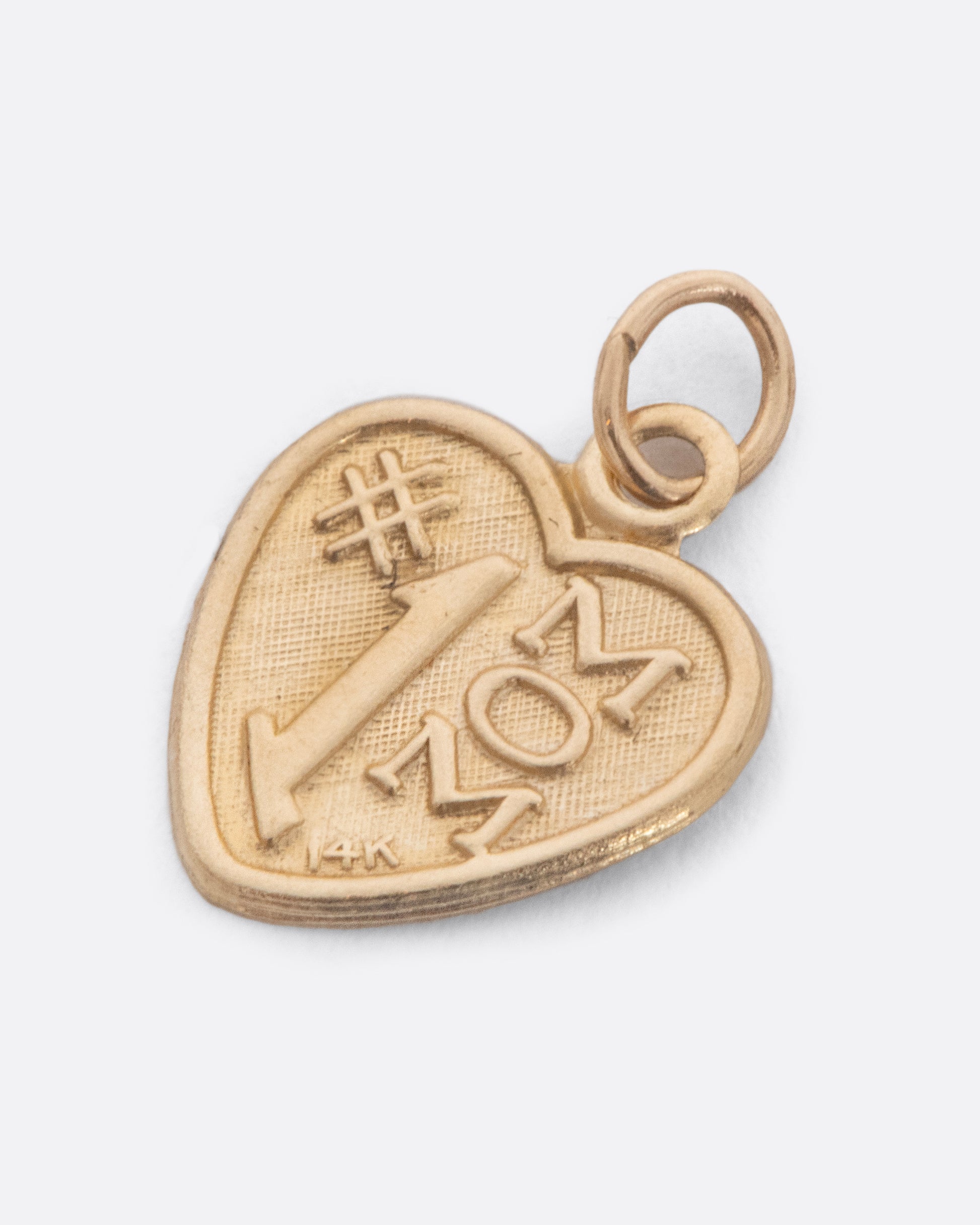 Gold heart shaped charm that reads '#1 Mom'. View from the side.