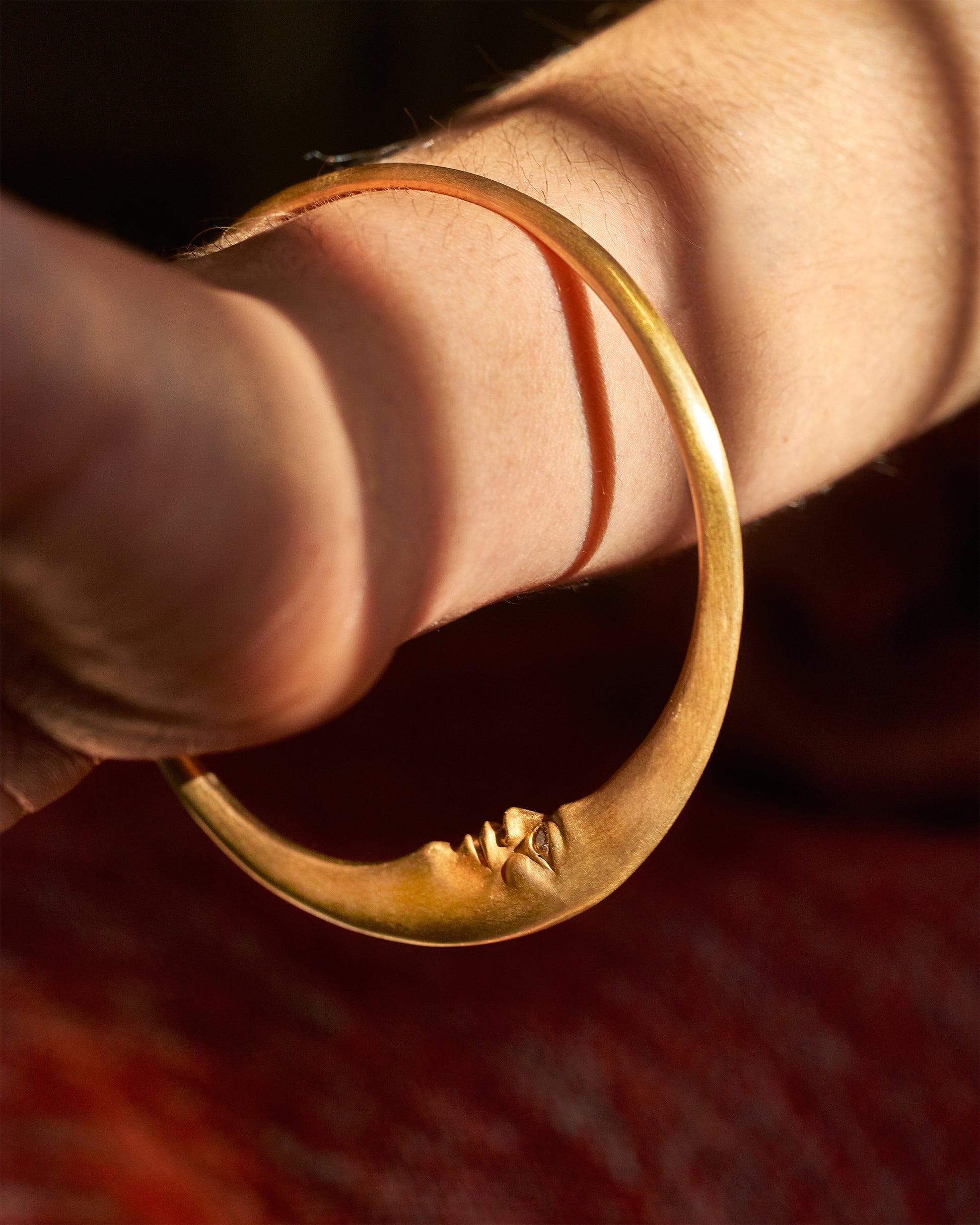 A solid gold bangle with a discreet moonface and sparkling diamond eyes.